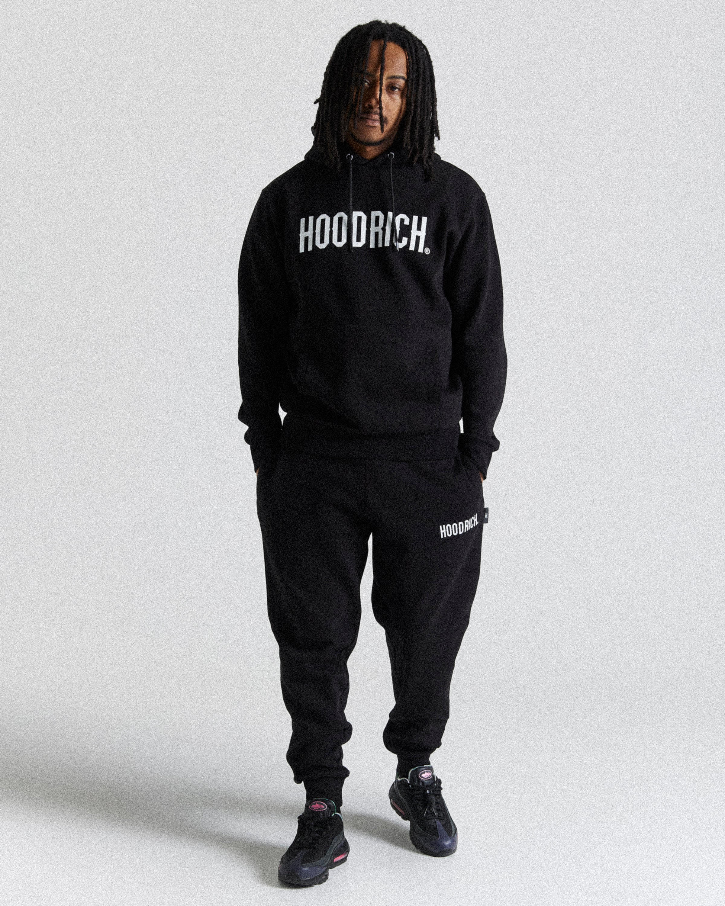 Displays a model wearing the Black 'Hoodrich' branded men's OG Core Full Tracksuit