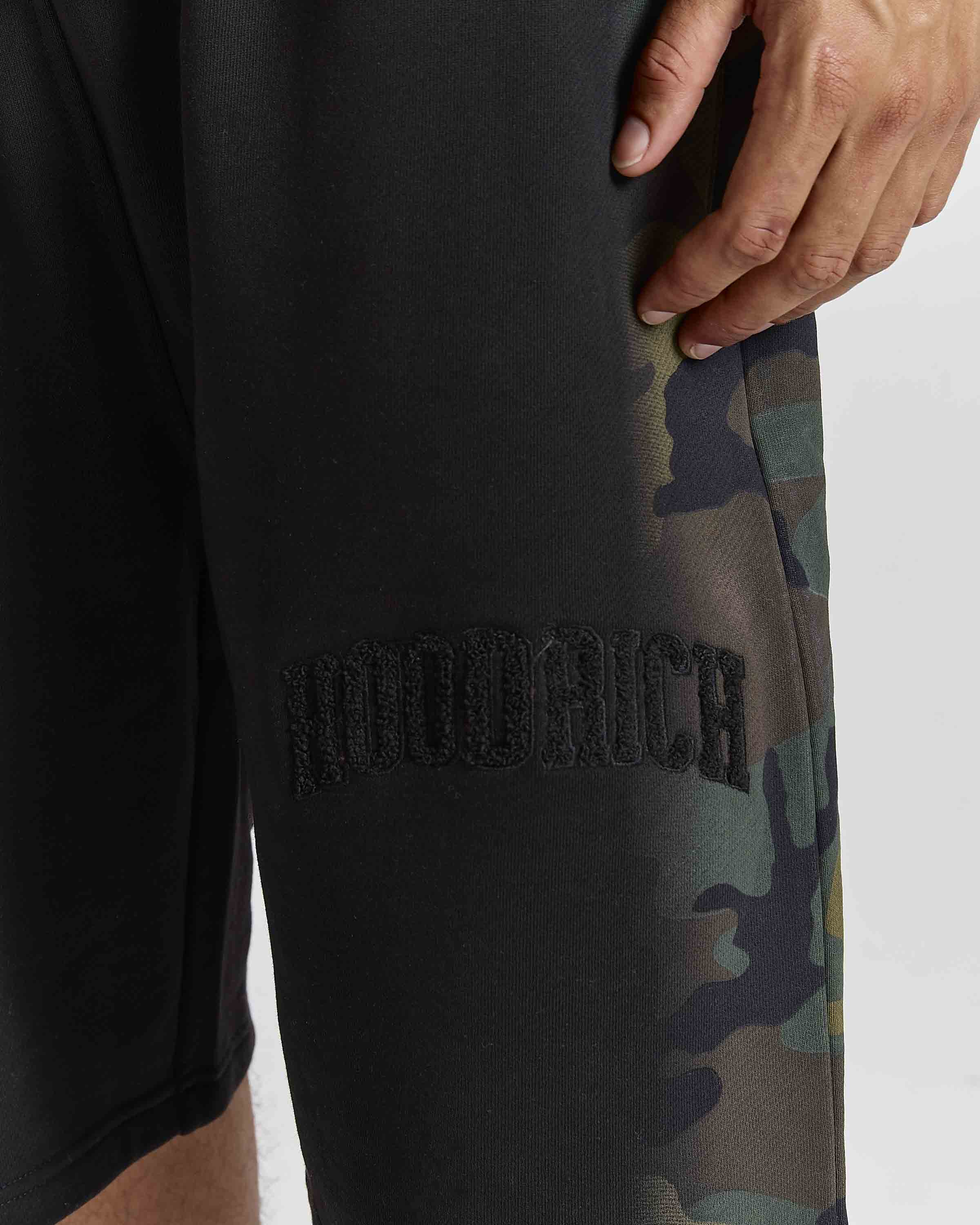 Displays a model wearing the Black Camo 'Hoodrich' branded men's Shade Matching Shorts Set