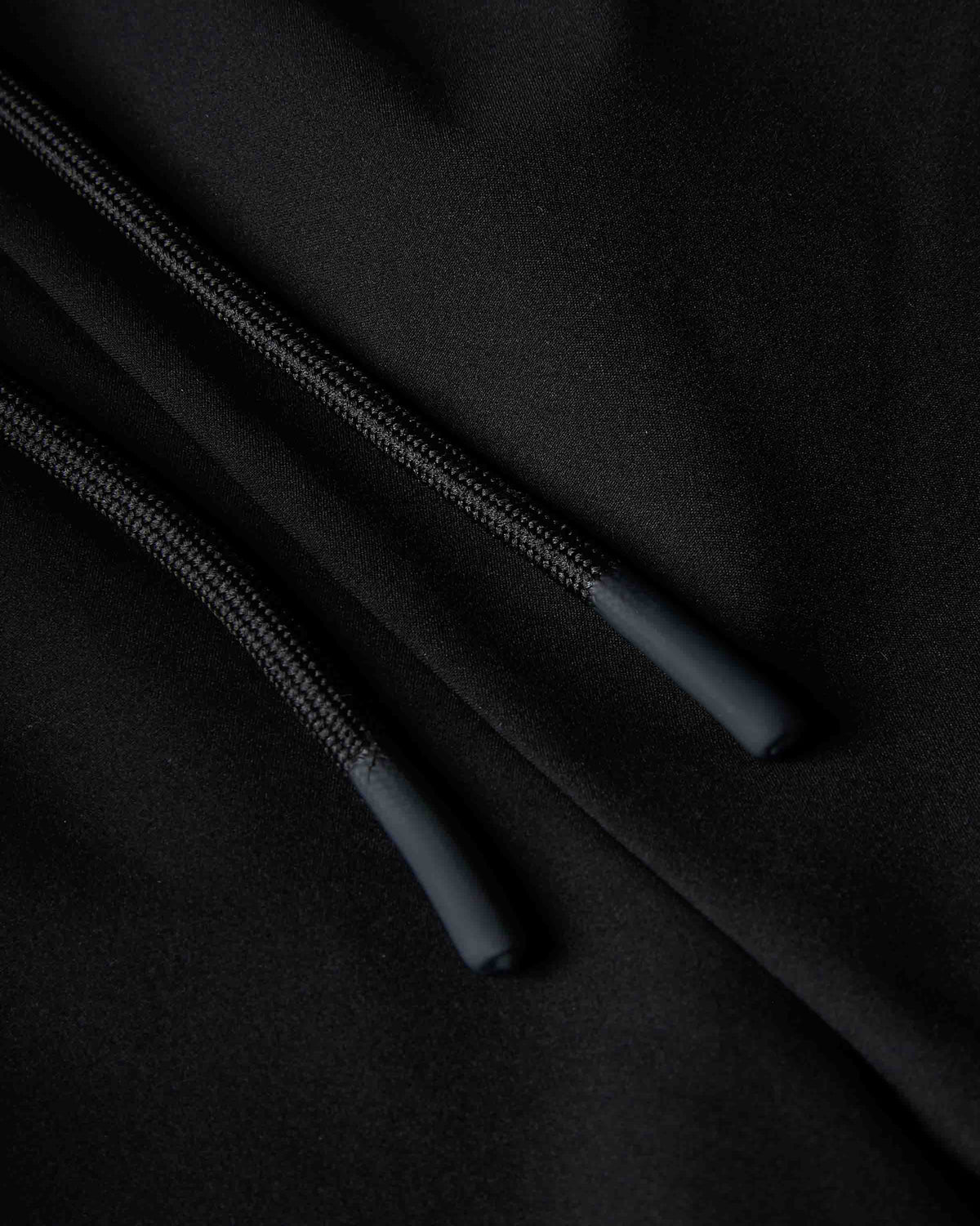 Close-up of a black hoodie showing the drawstring cords and ribbed fabric texture.