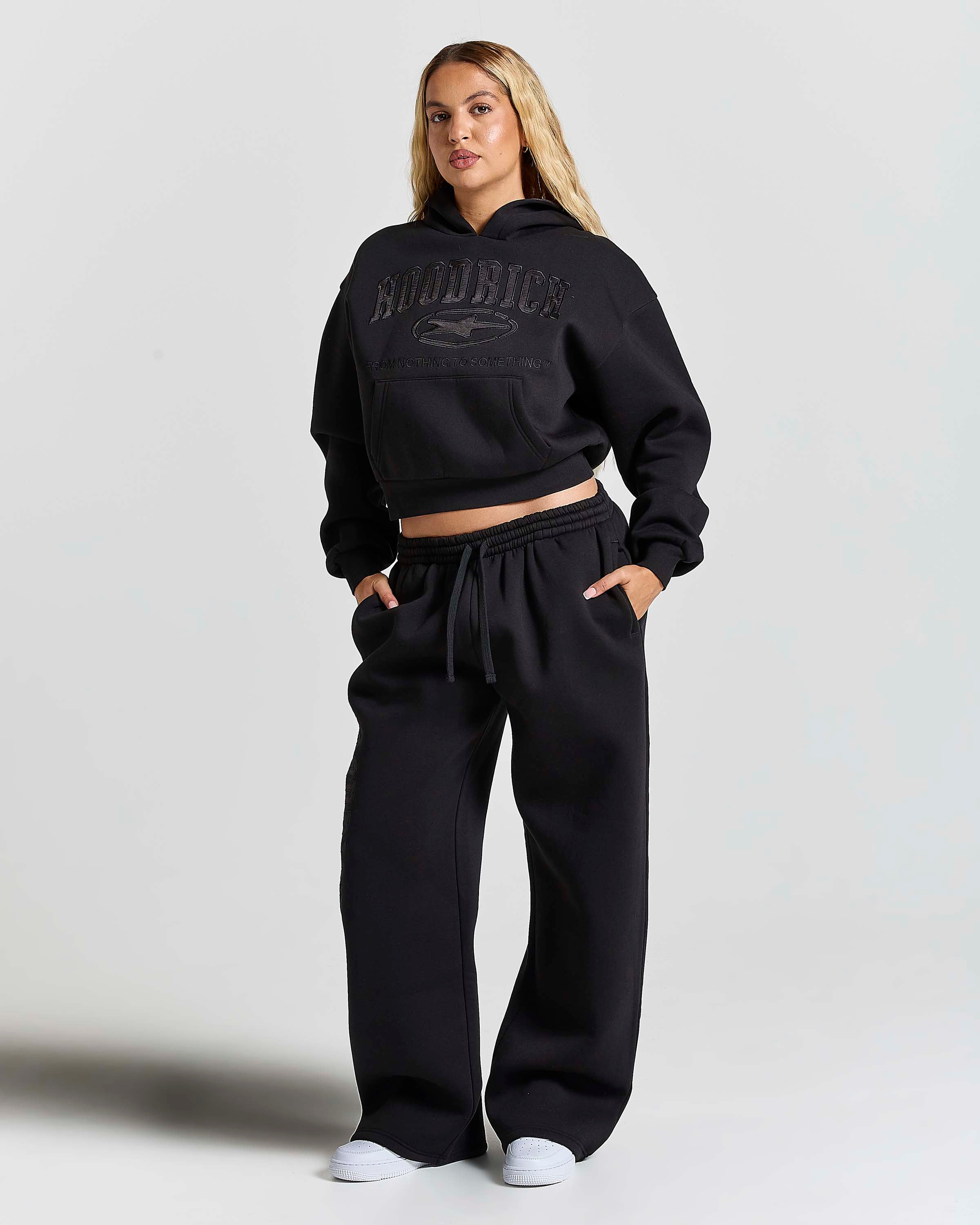 Displays a women wearing the Black 'Hoodrich' branded women's Aegis Full Tracksuit