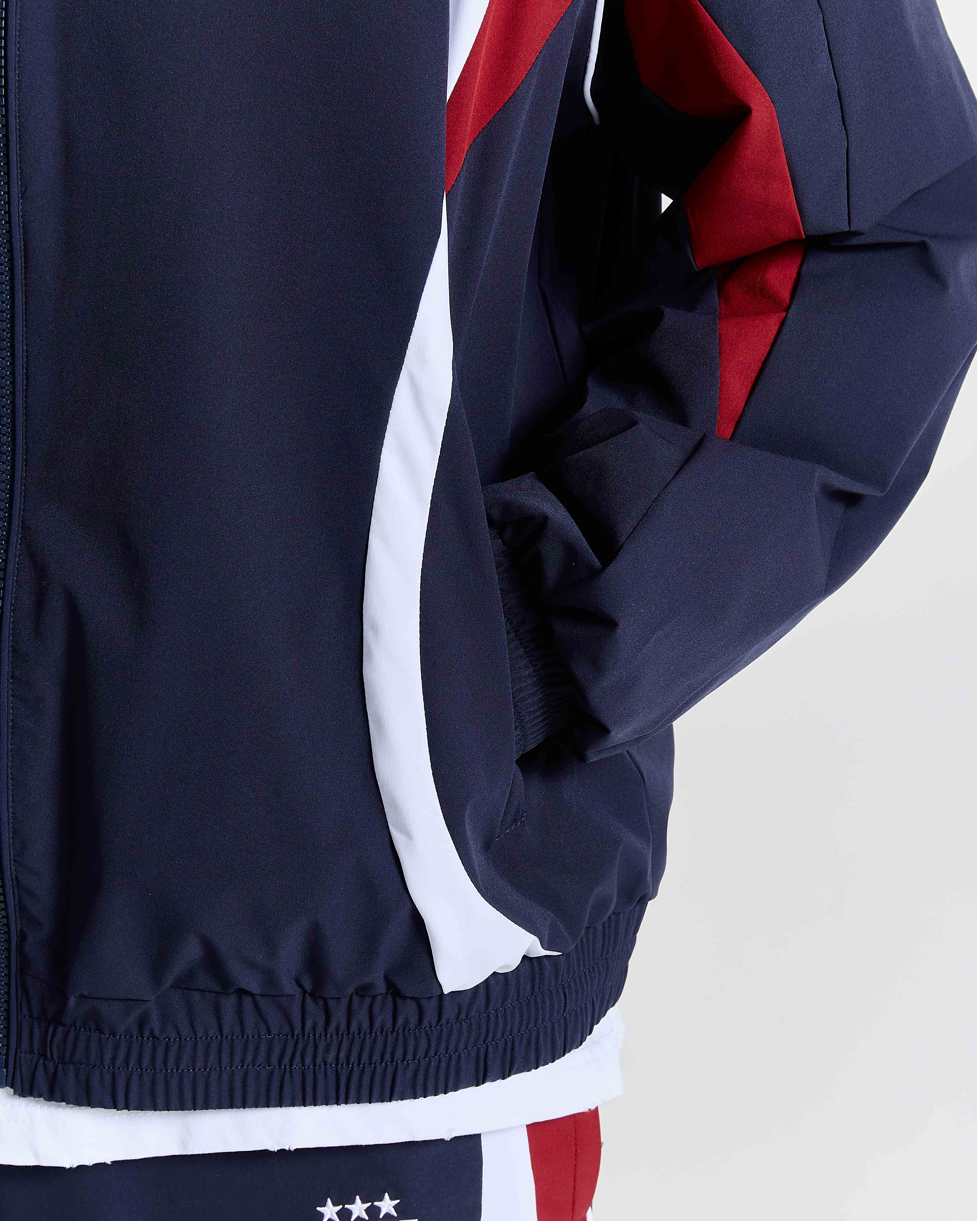 Navy tracksuit with red and white accents on a light gray background