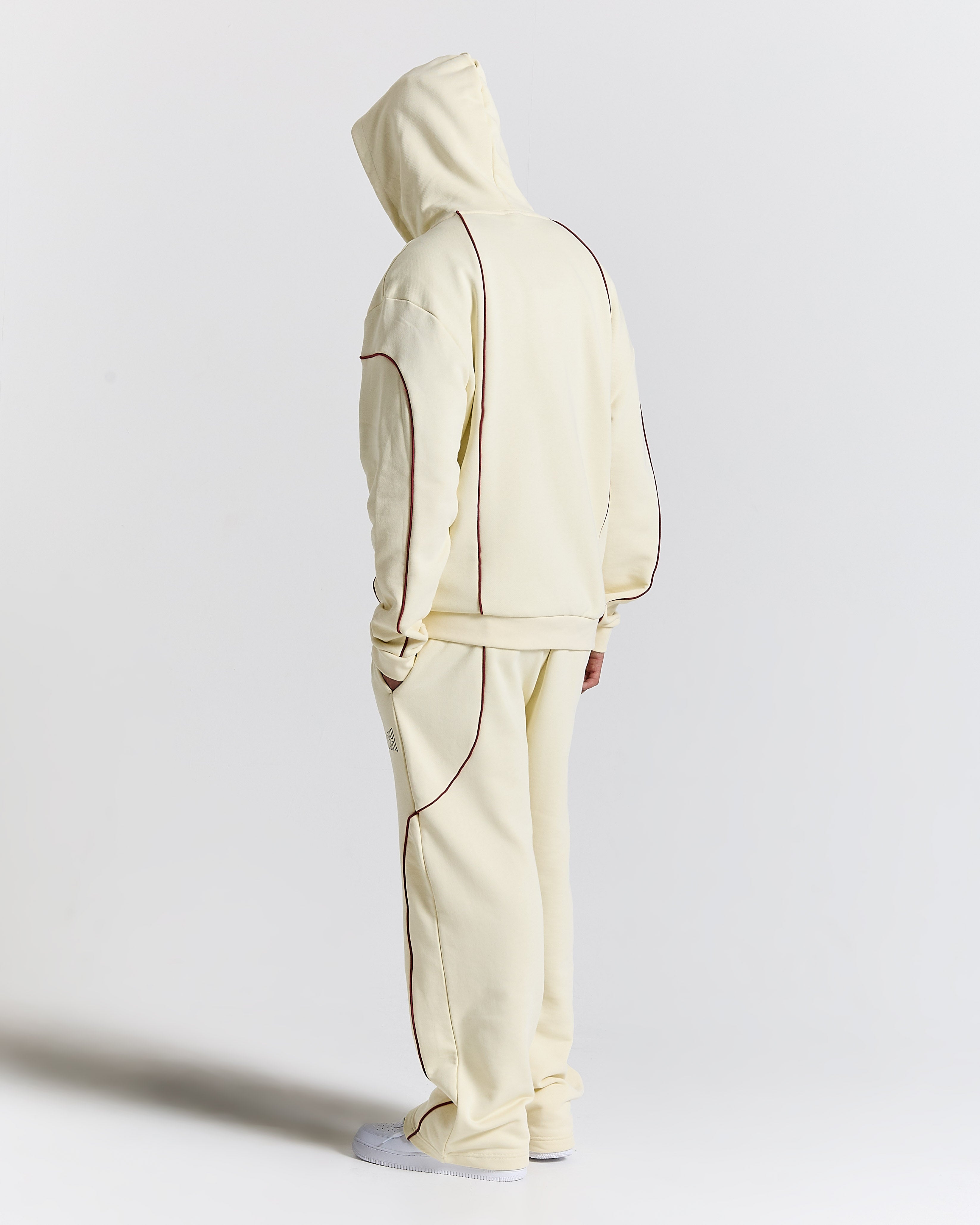 Person wearing a cream-colored tracksuit on a light gray background