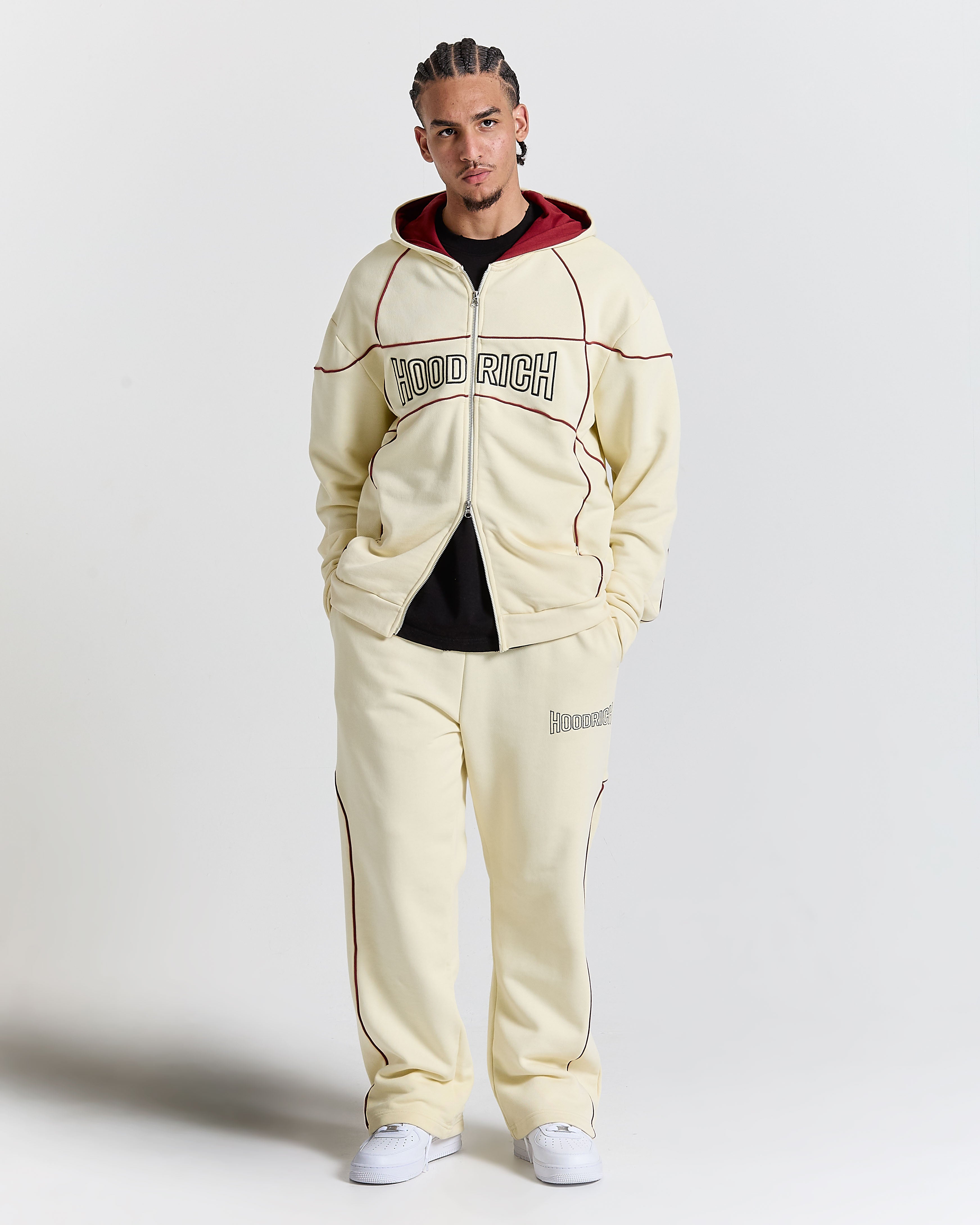 Person wearing a cream tracksuit with 'HOODRICH' branding on a white background