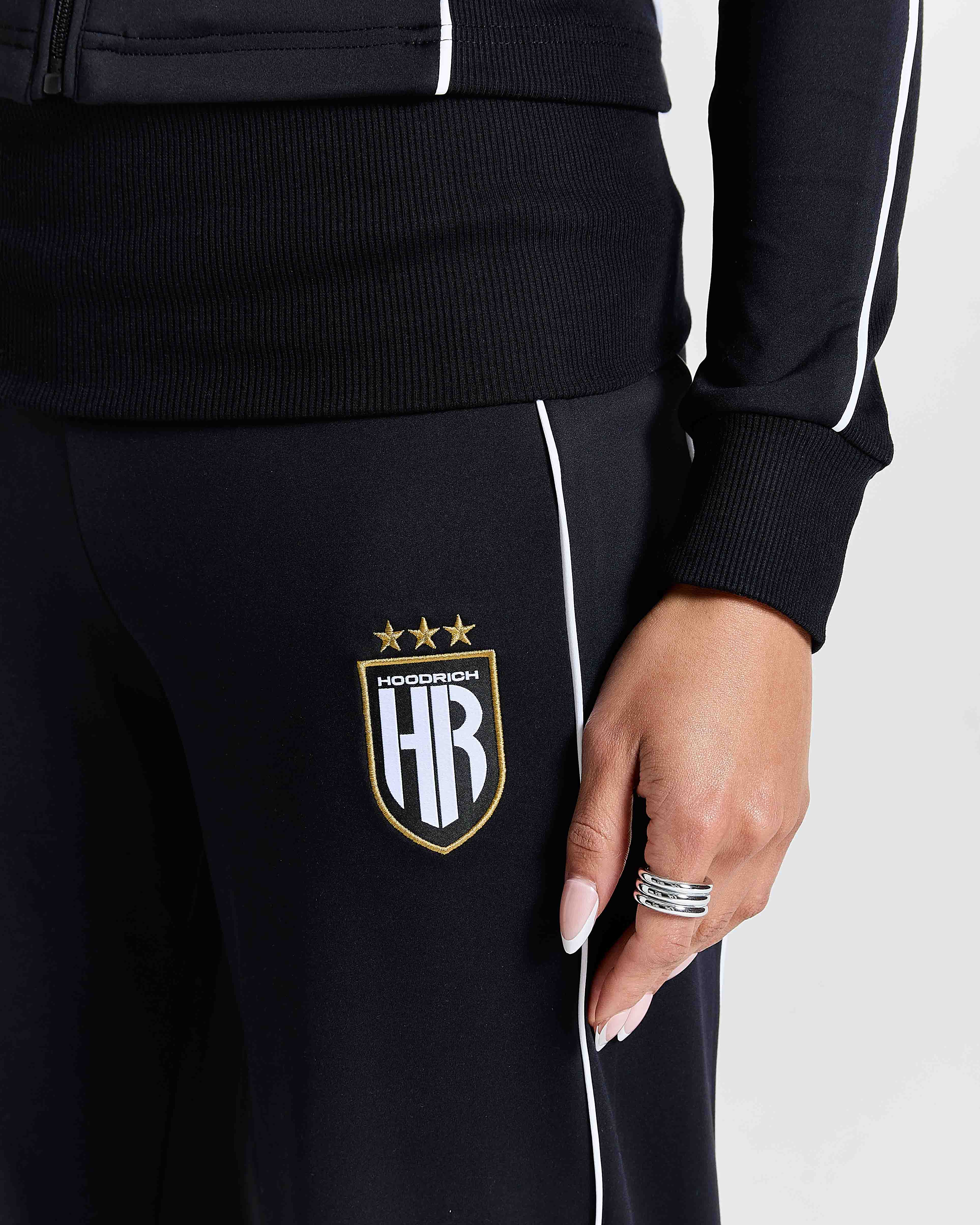 Black tracksuit with a logo on the pants against a white background