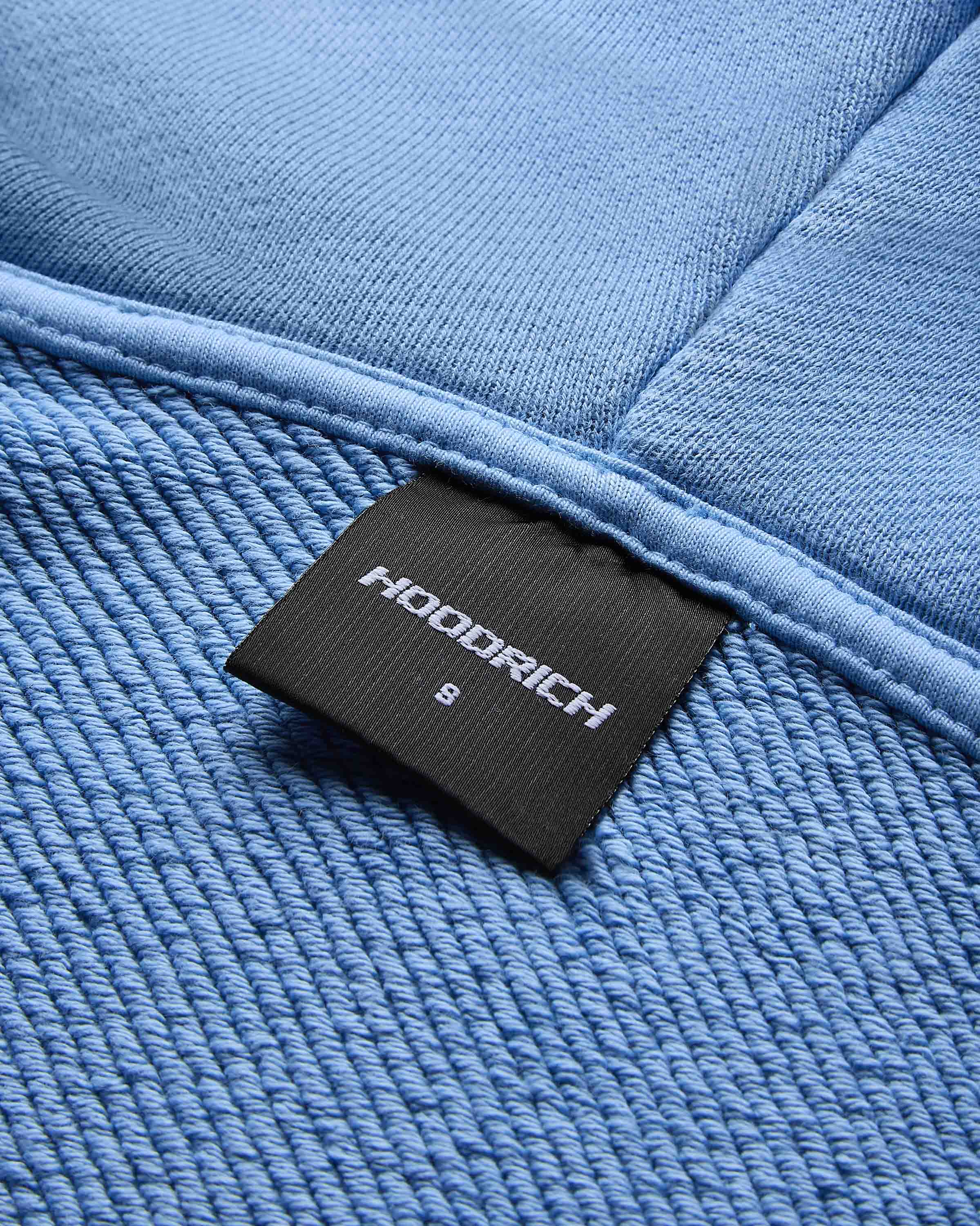 Close-up of the internal Hoodrich neck label showing size small on the blue cropped hoodie.