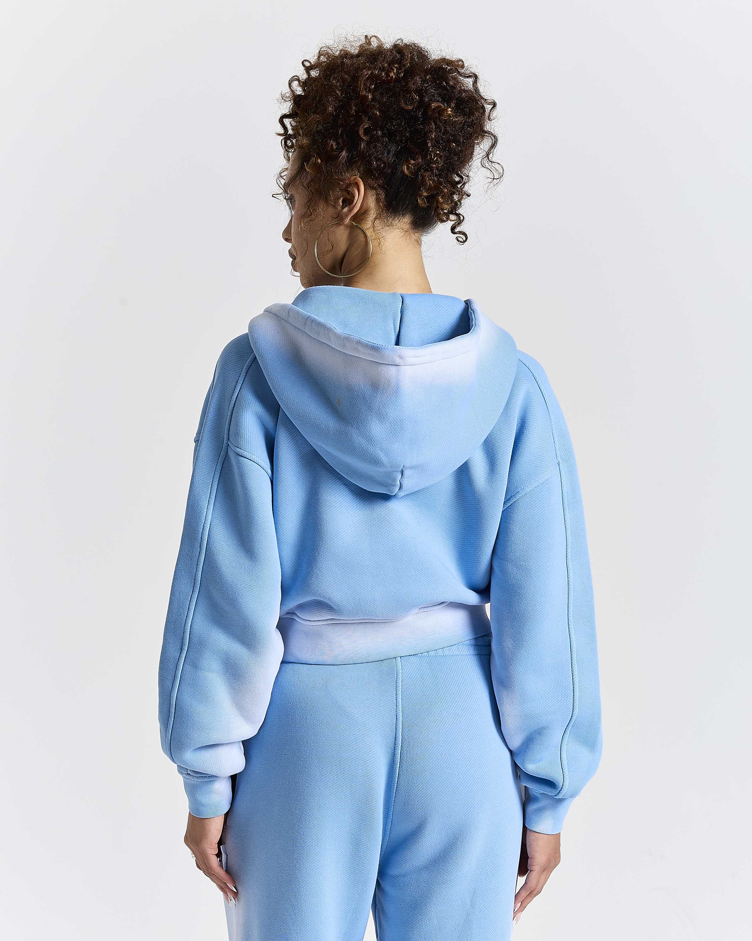 Model seen from behind wearing a blue ombre cropped hoodie.