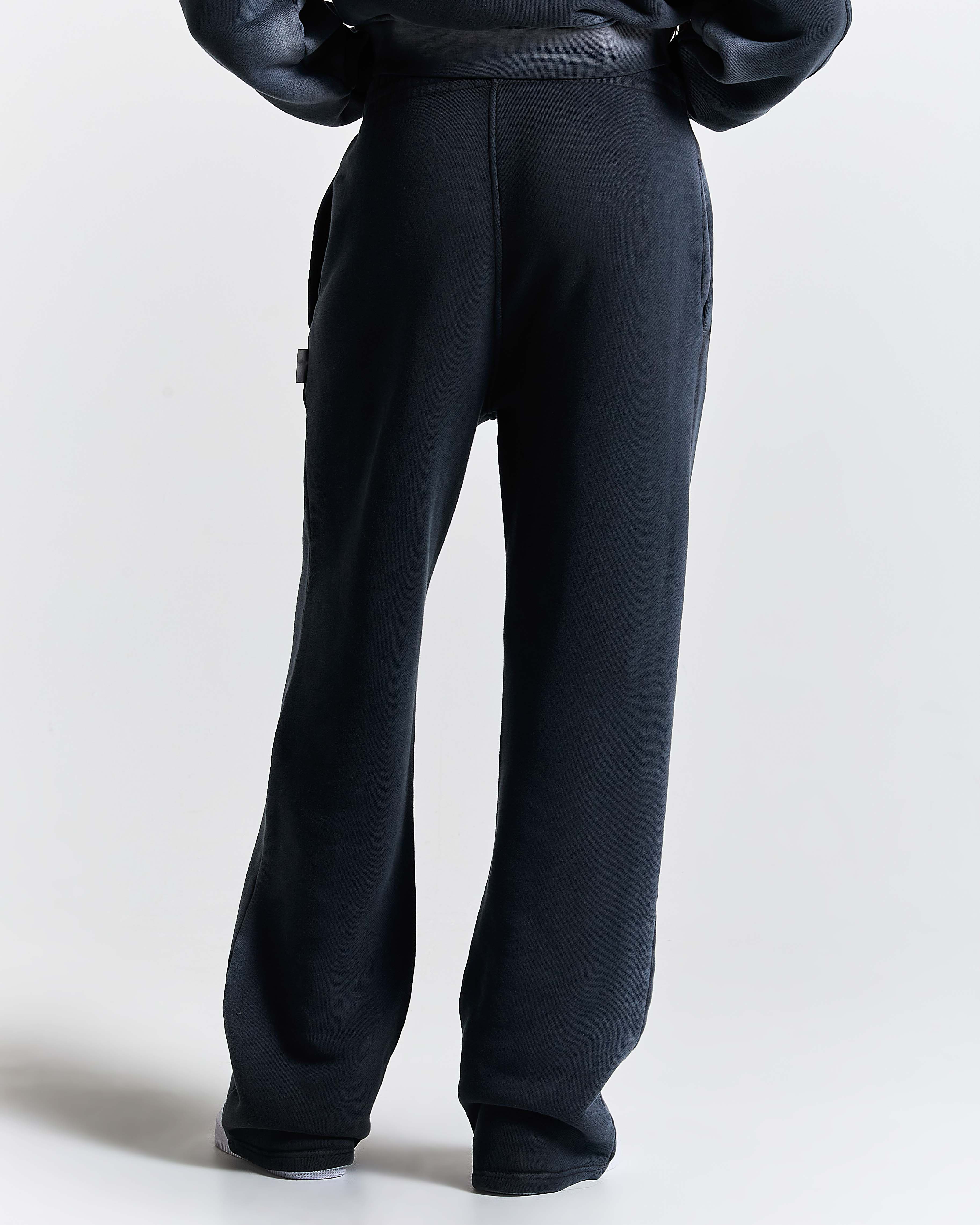 Back view of a female model wearing black wide-leg joggers.