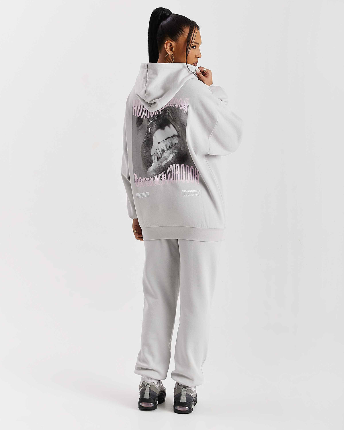 Displays a model wearing the Grey 'Hoodrich' branded women's Flex Full Tracksuit