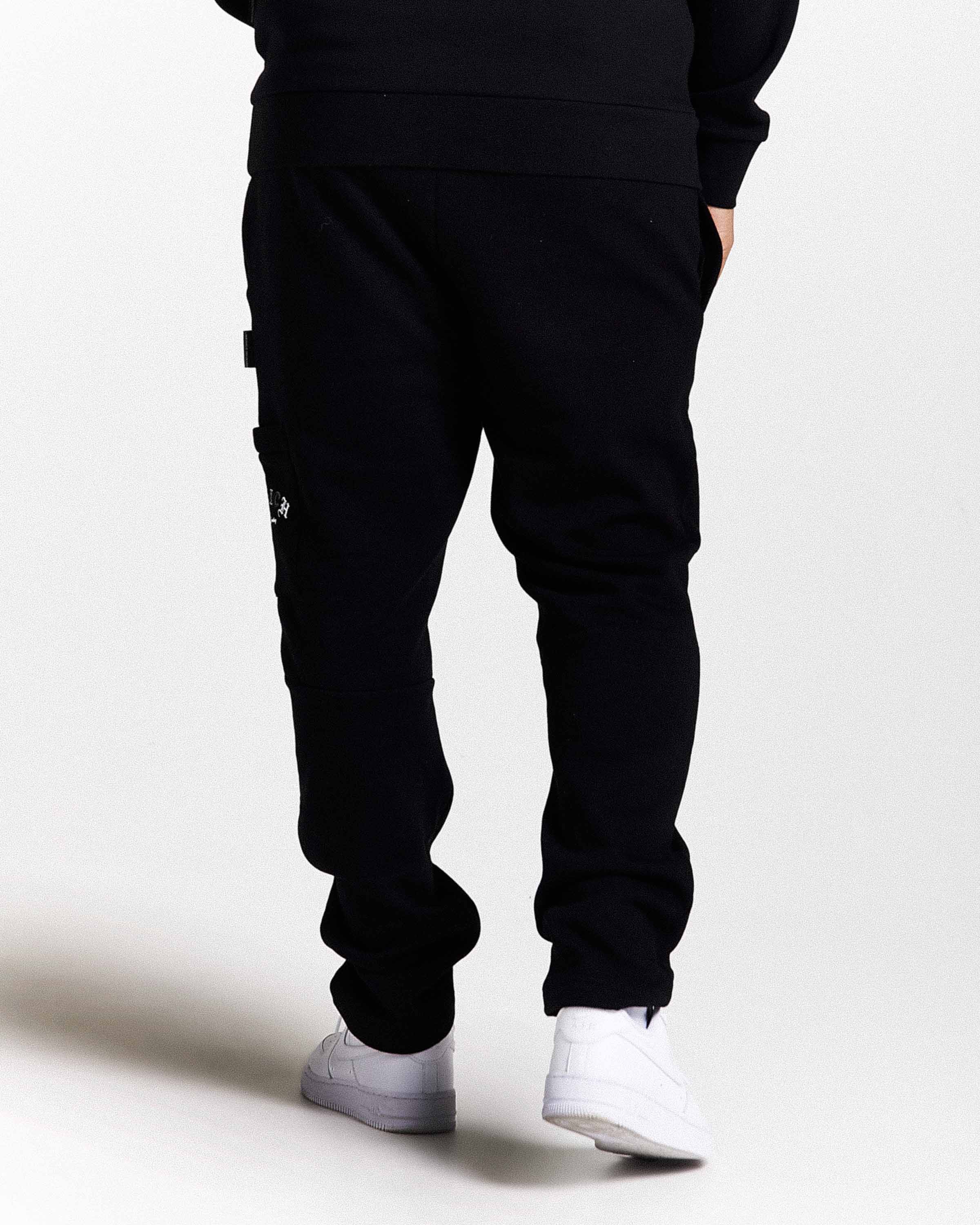 Person wearing black jogger pants with a small logo on a white background