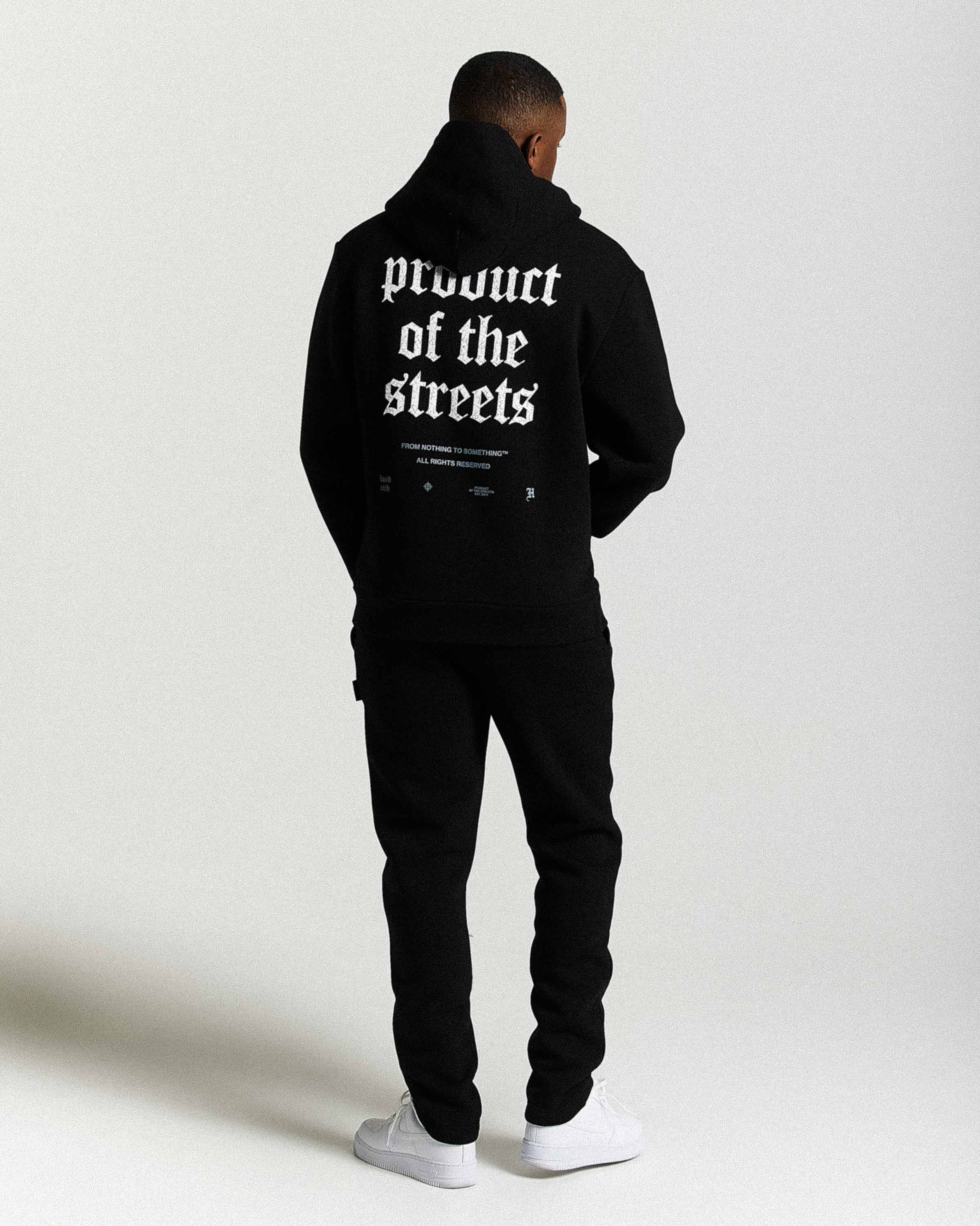 Displays a model wearing the Black 'Hoodrich' branded men's Shadow Full Tracksuit
