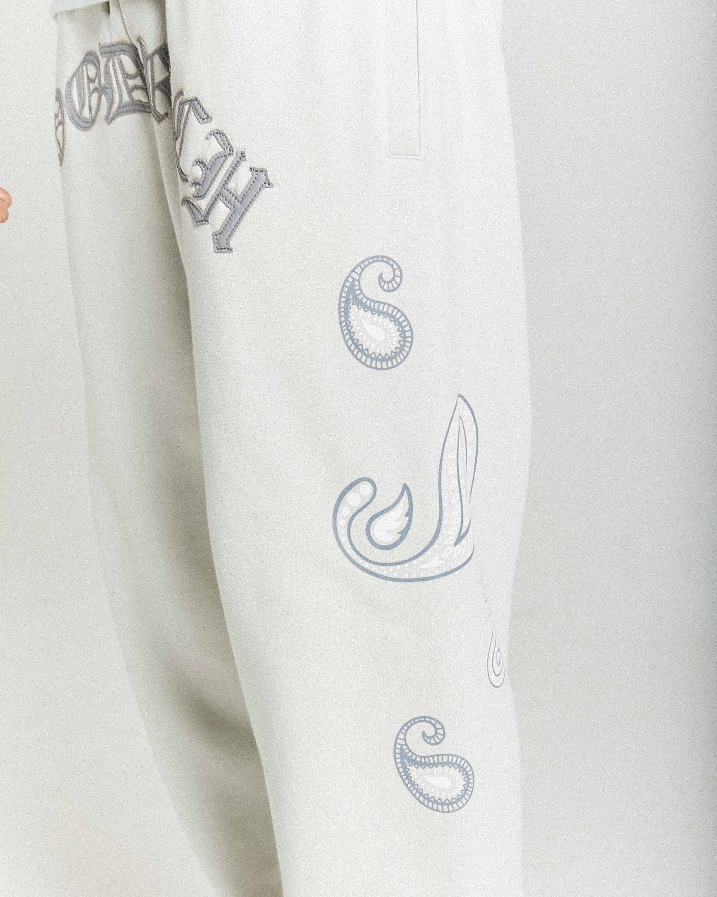 White pants with embroidered designs on a white background