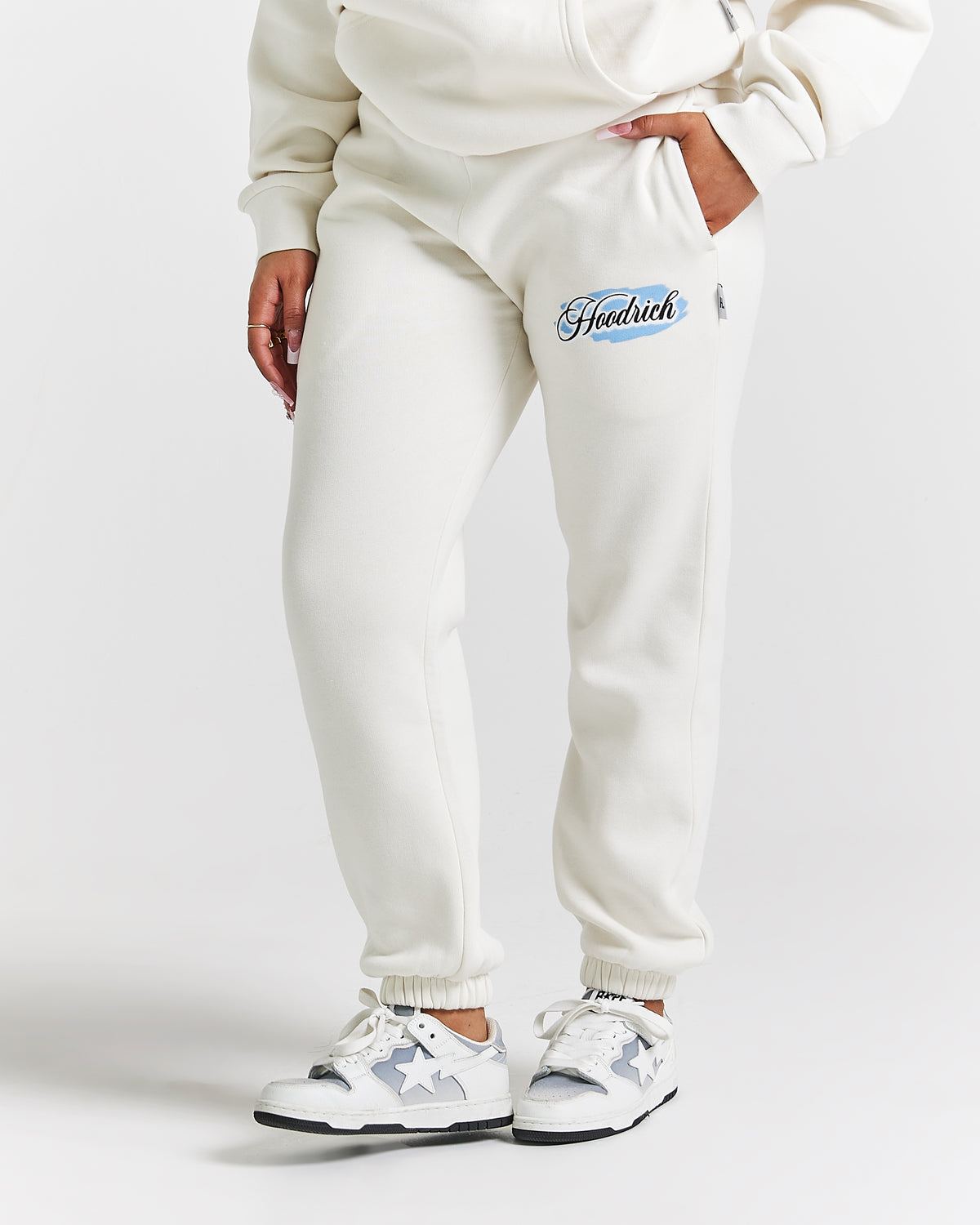 Displays a model wearing the White 'Hoodrich' branded women's Grillz Full Tracksuit