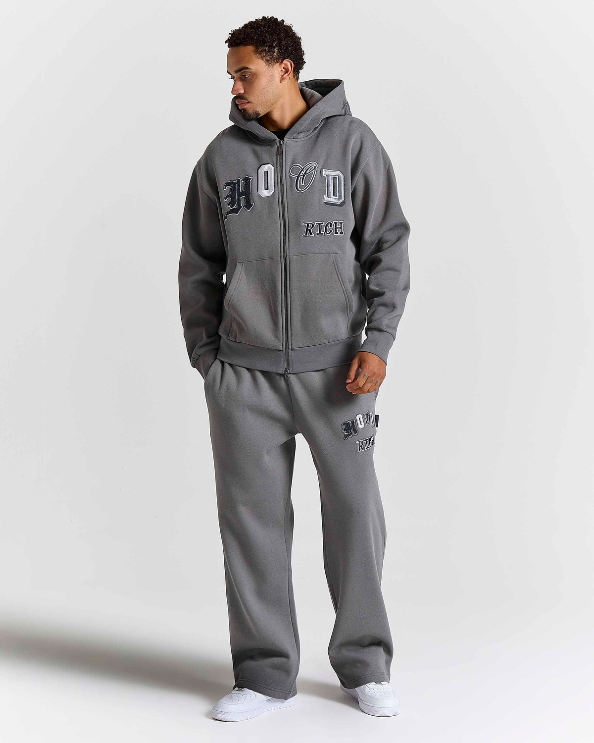 Displays a model wearing the grey lava smoke 'Hoodrich' branded Forza Oversized Wide Leg Jogger 