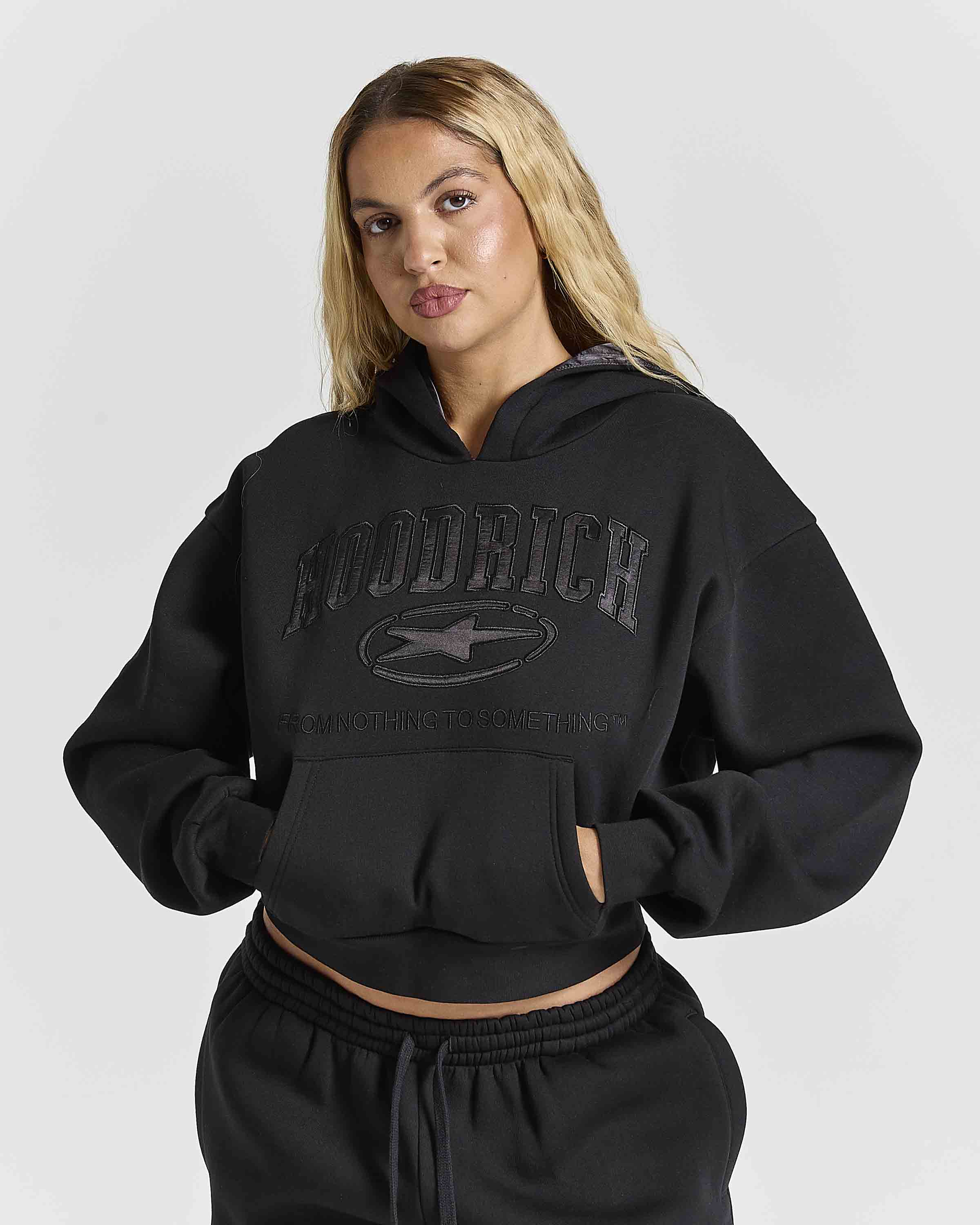 Displays a women wearing the Black 'Hoodrich' branded women's Aegis Full Tracksuit