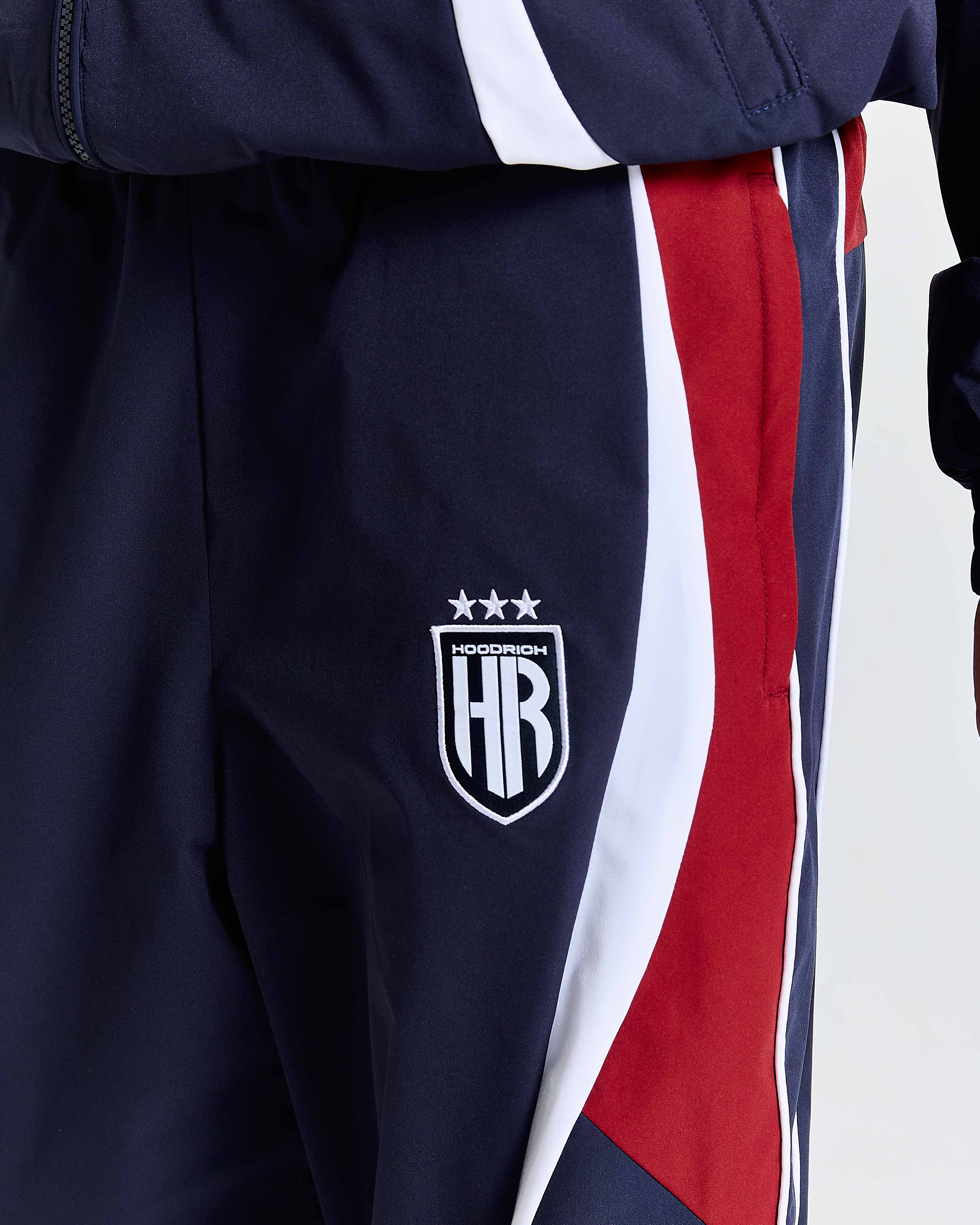 Navy tracksuit with red and white stripes featuring a logo on a white background