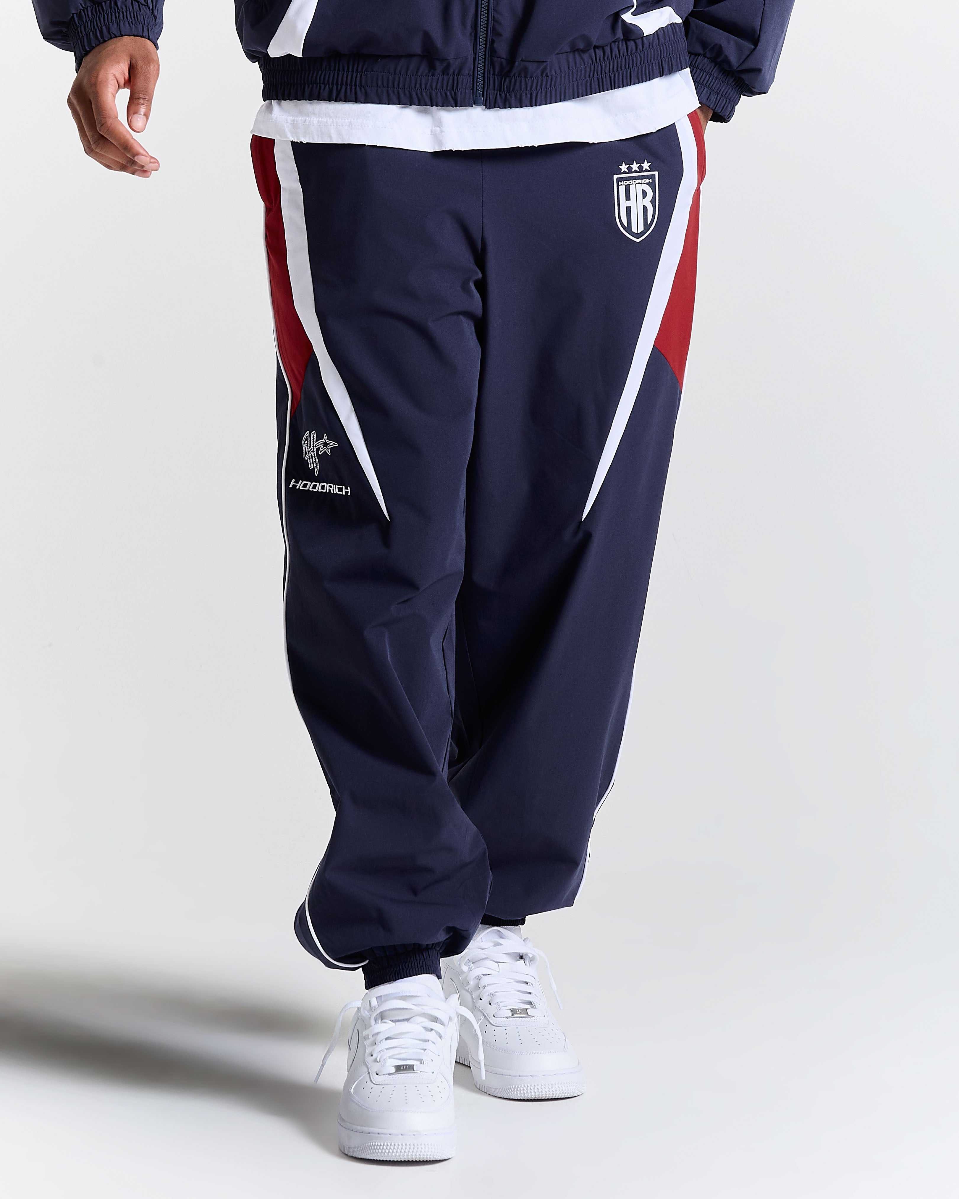 Navy tracksuit with red and white accents on a plain background