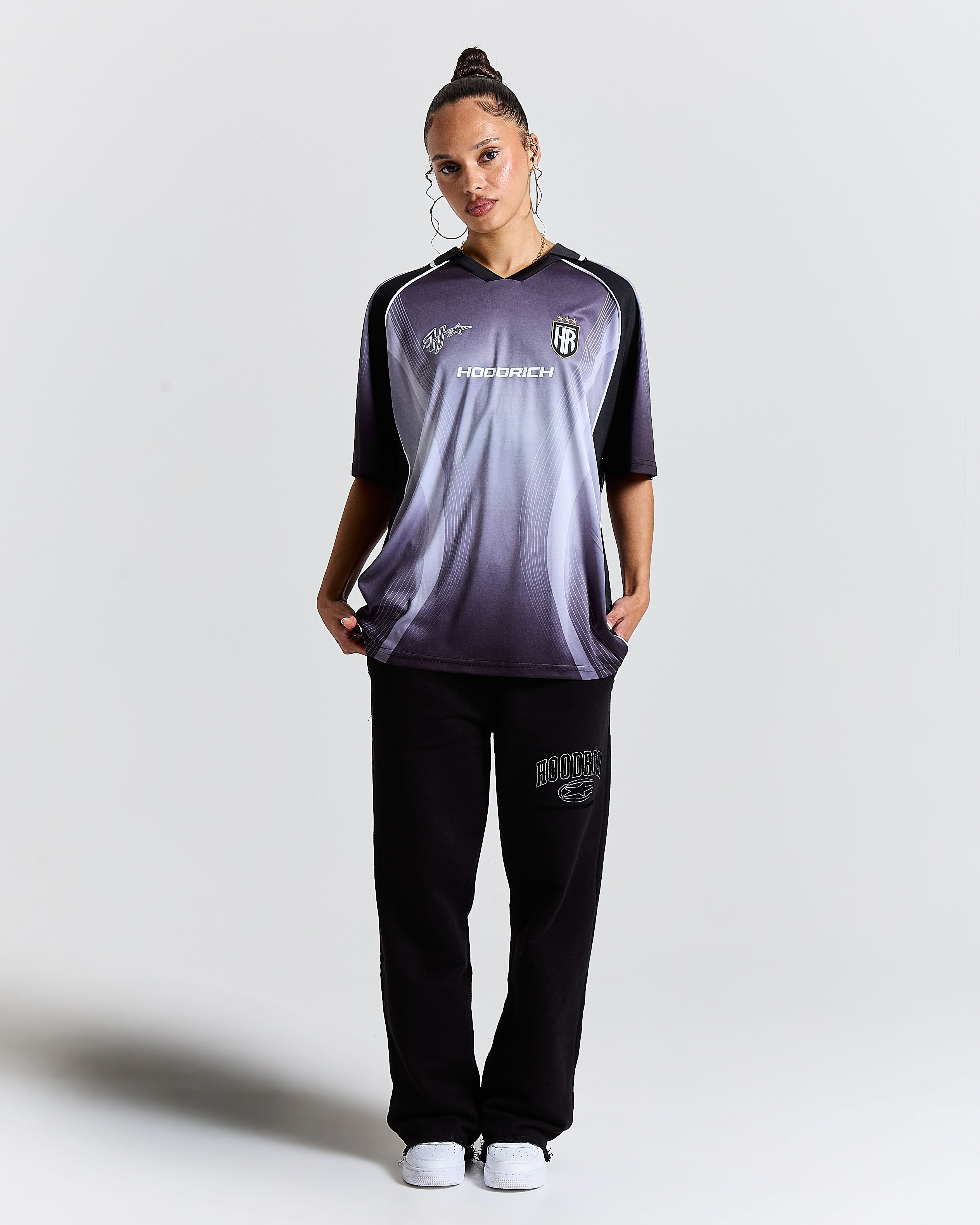 Person wearing a sports outfit with a brand logo on a plain background