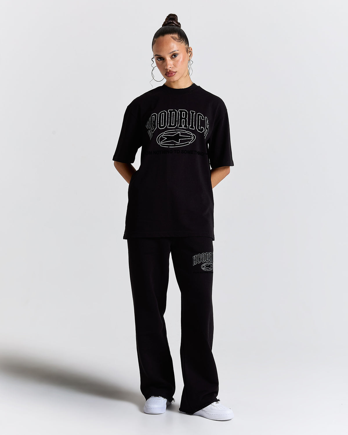 Person wearing a black 'Hoodrich' t-shirt and pants on a white background
