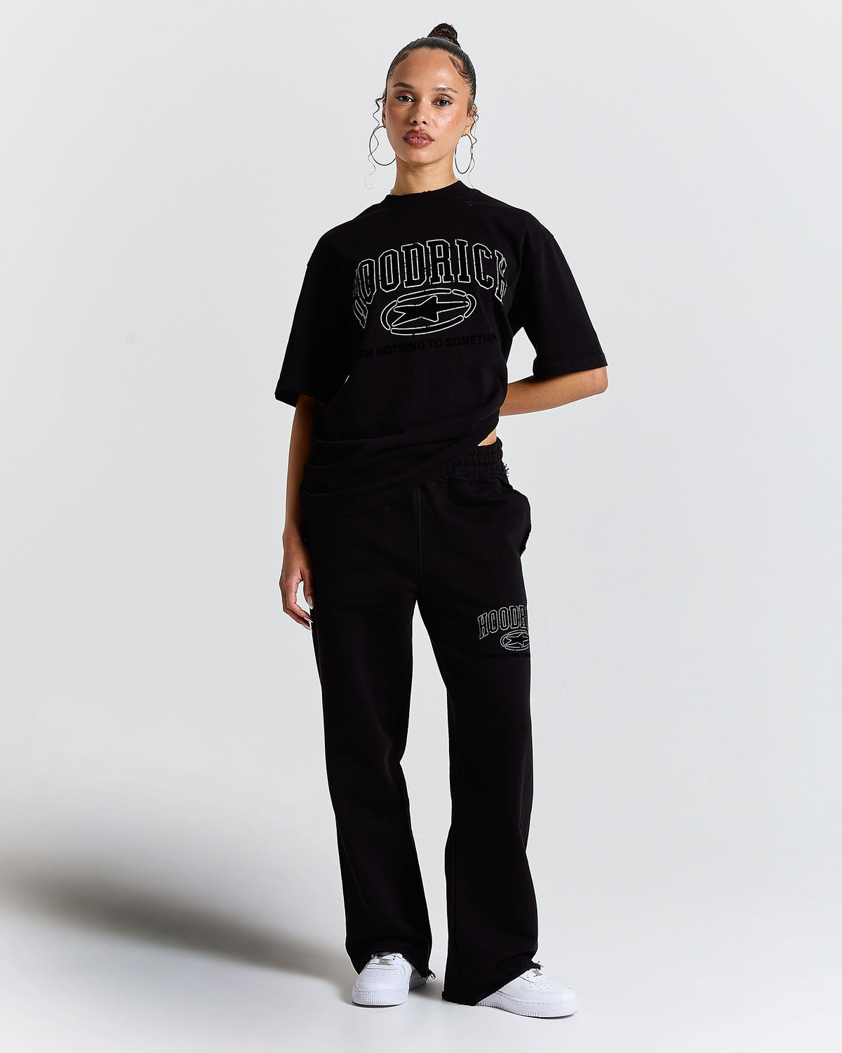 Person wearing a black 'Hoodrich' t-shirt and pants on a white background