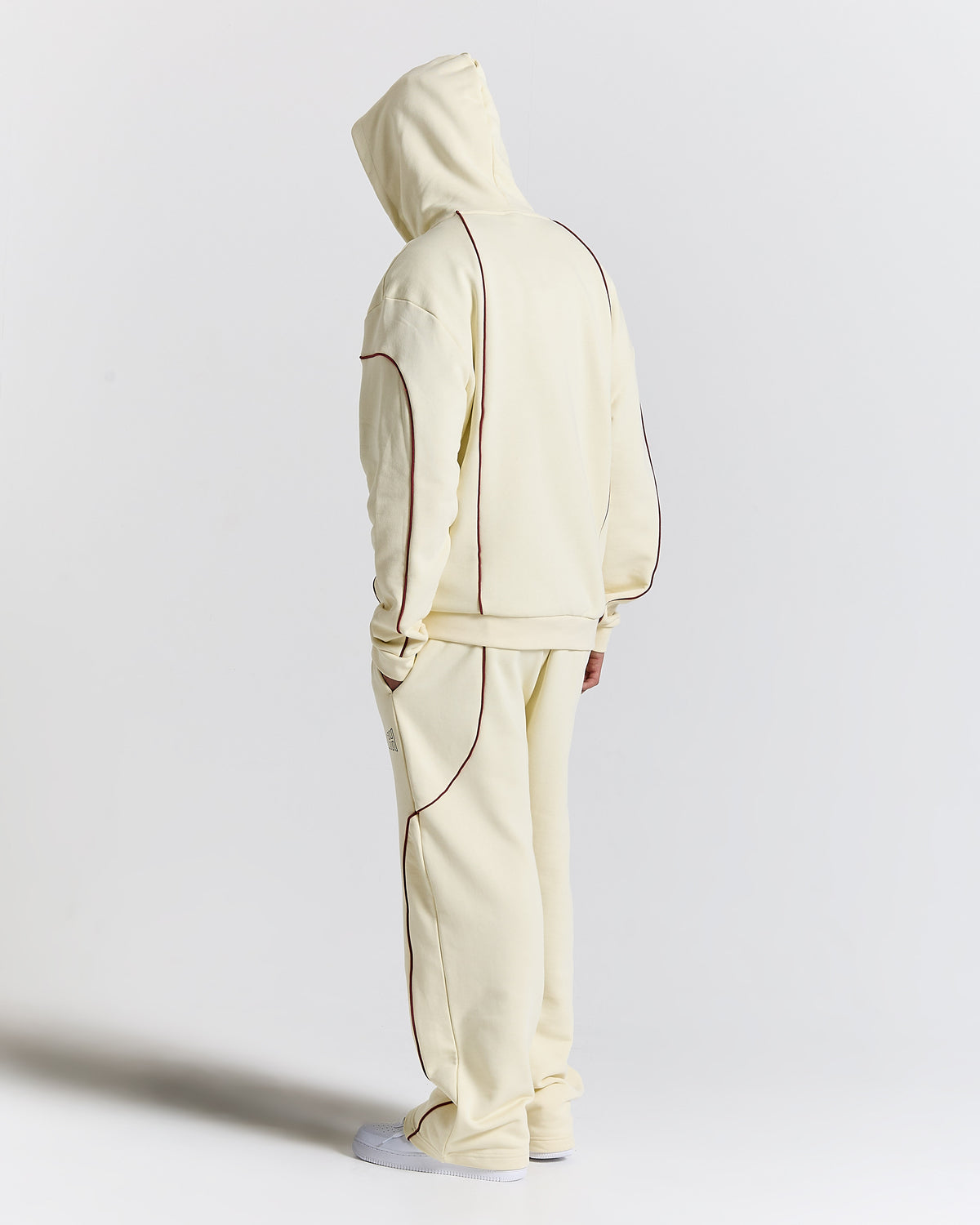 Person wearing a cream-colored tracksuit on a light gray background