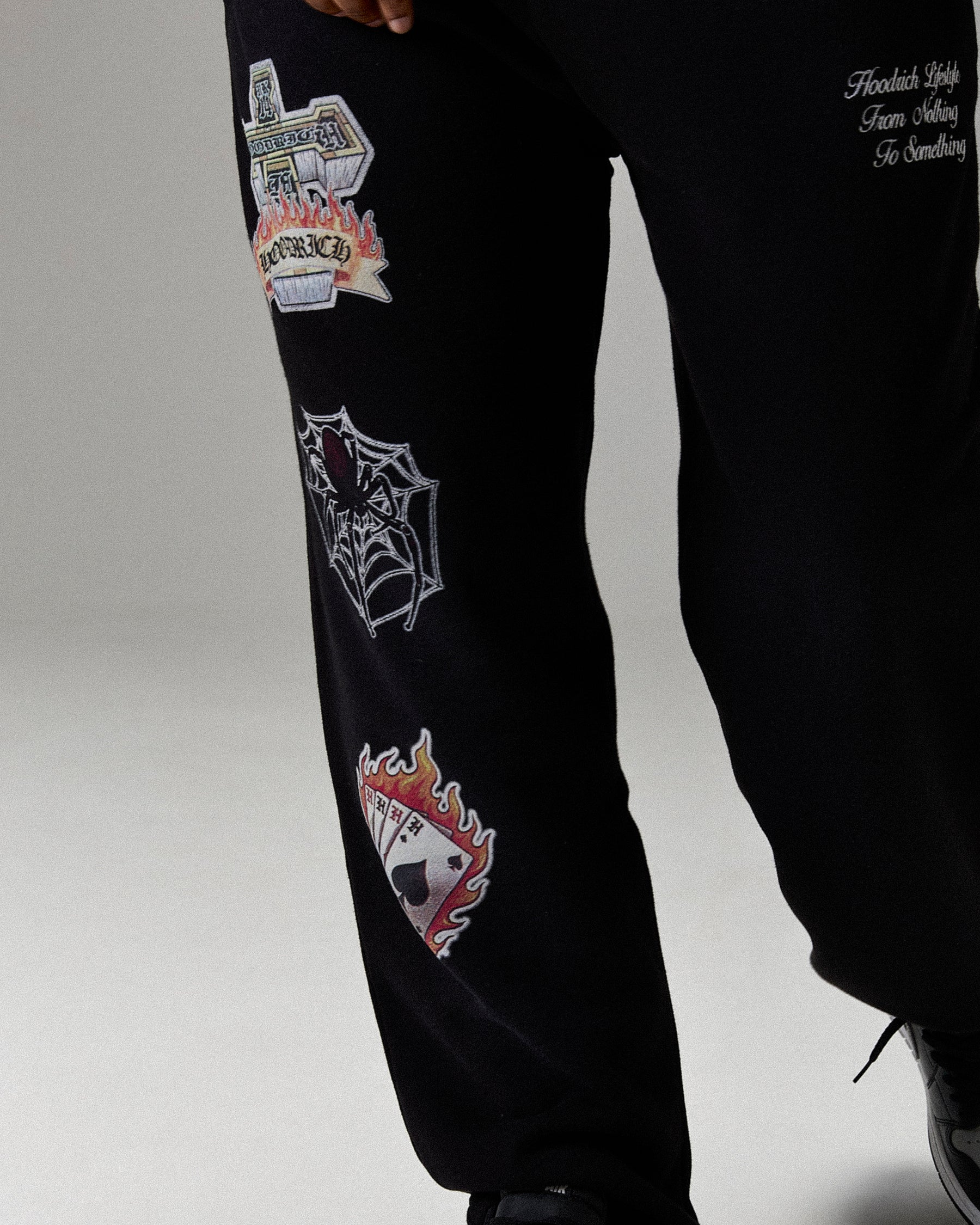Black pants with colorful patches on a light gray background