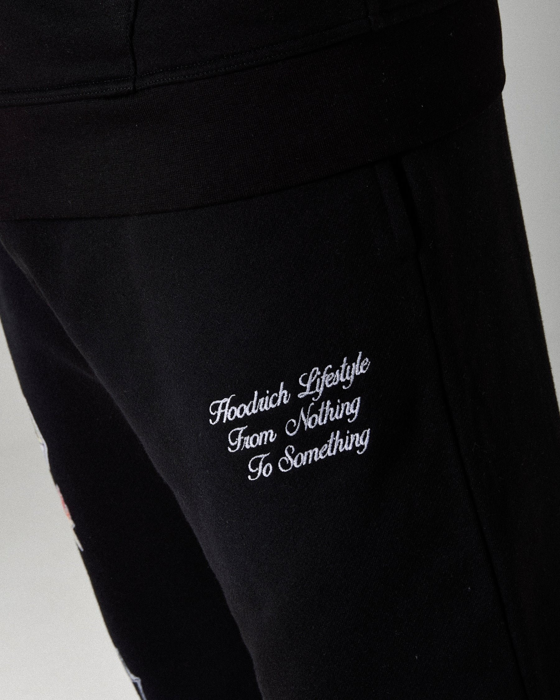 Black pants with white text saying 'Hoodrich Lifestyle From Nothing to Something' on a white background