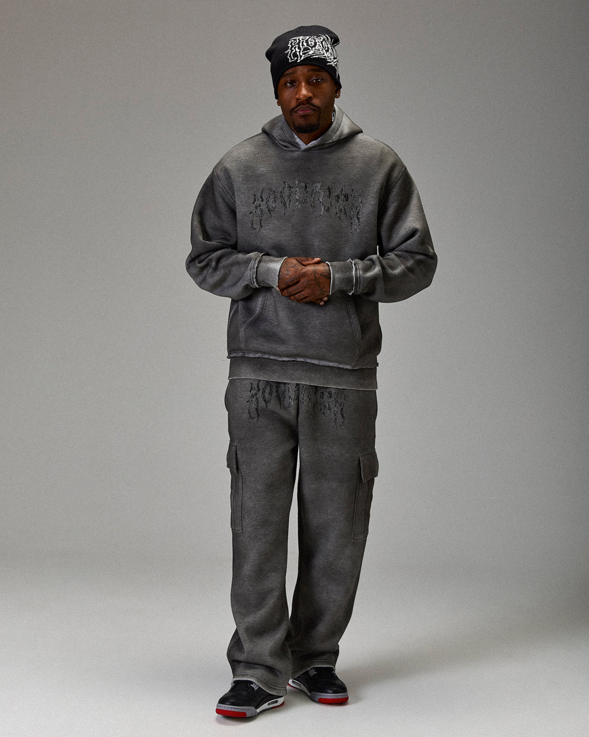 Person wearing a gray hoodie and pants set on a plain background