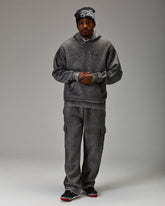 Person wearing a gray hoodie and pants set on a plain background