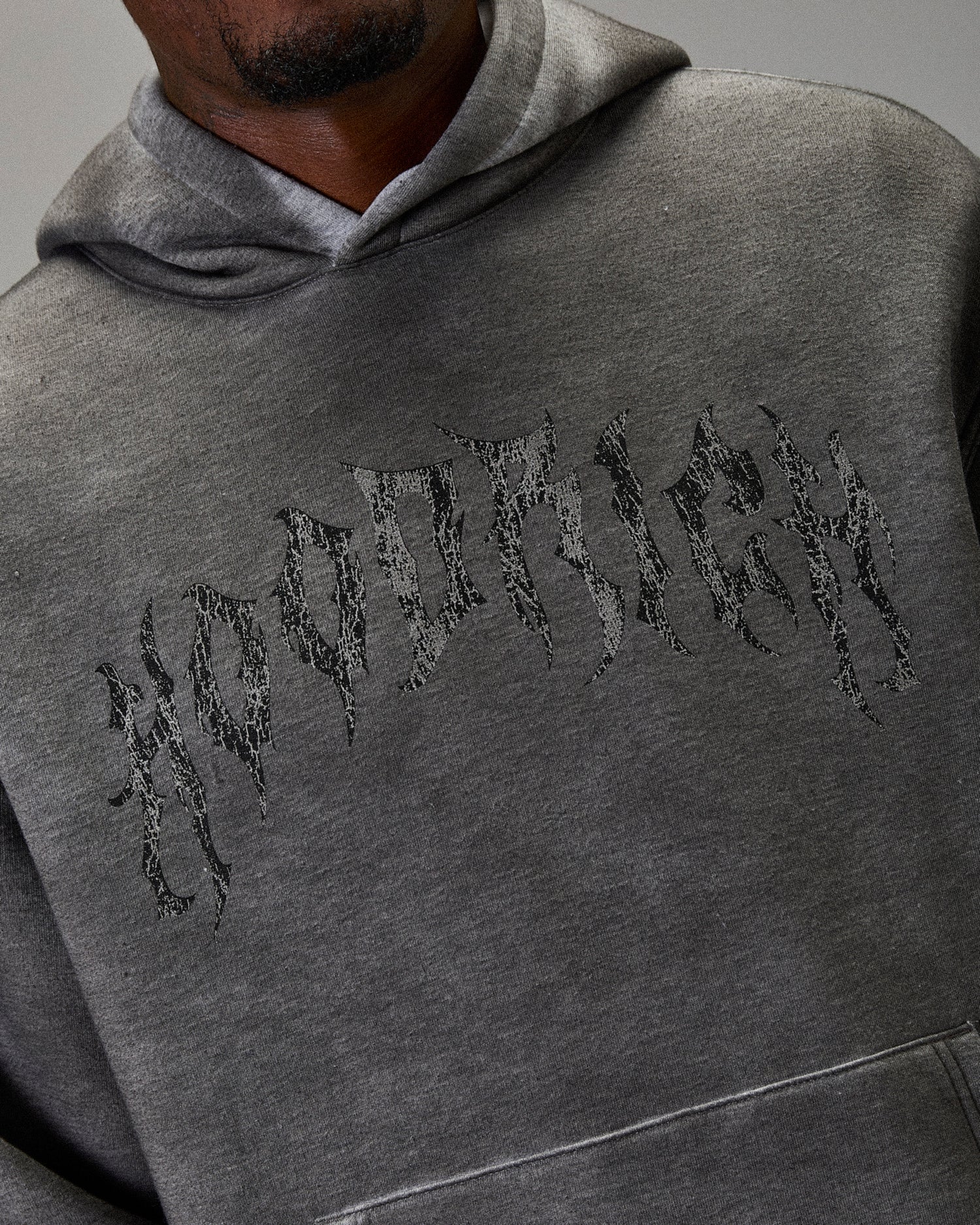 Gray hoodie with embroidered text on a gray background. Hoodie says "Hoodrich"