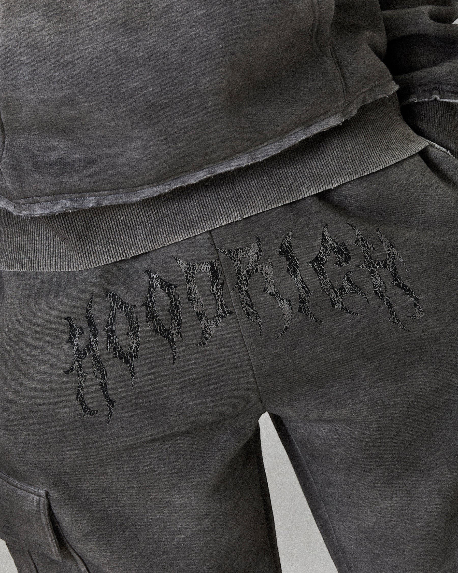 Gray sweatpants with embroidered text on a plain background