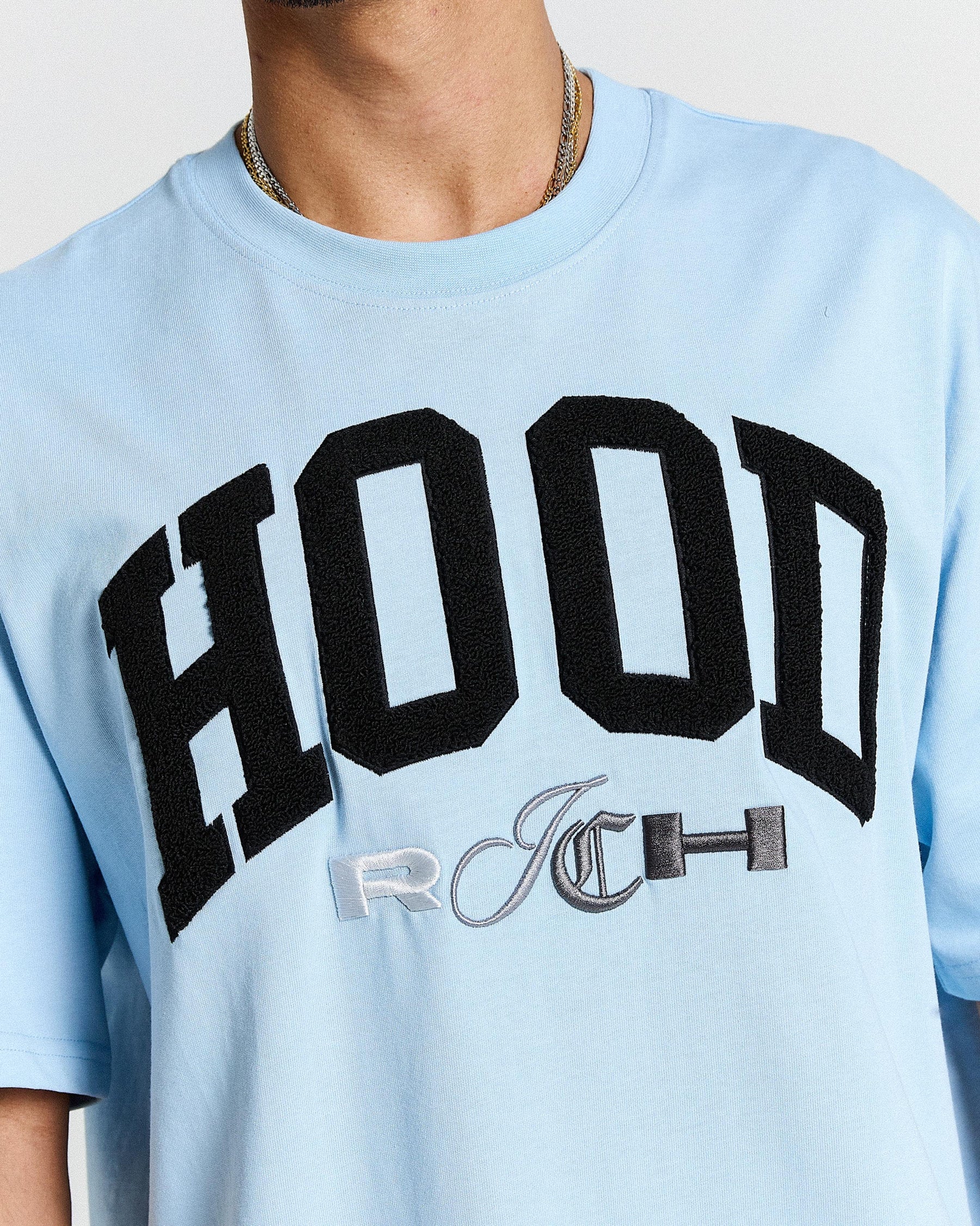 Light blue t-shirt with black and gray text on a neutral background