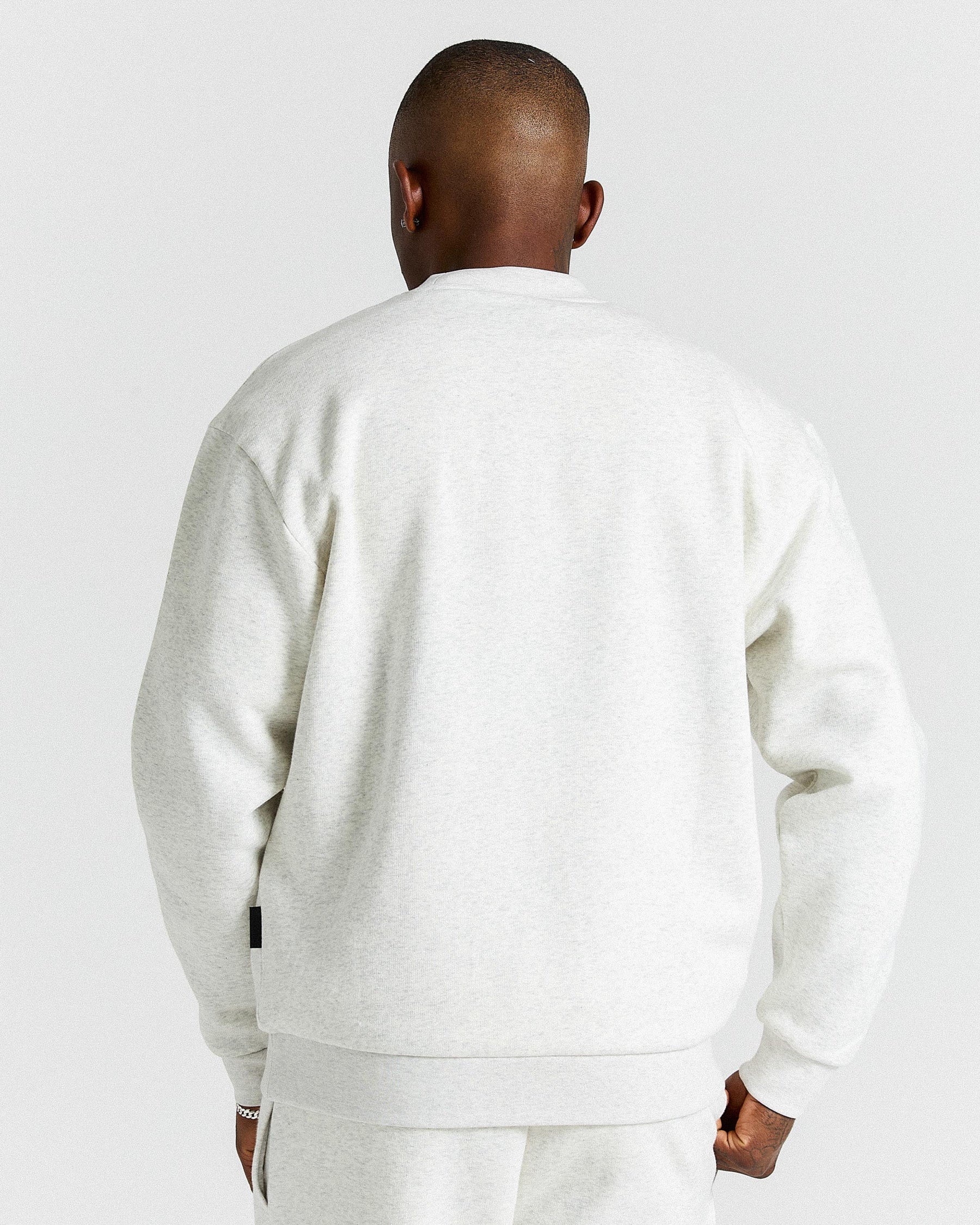 Person wearing a light grey tracksuit against a plain background.