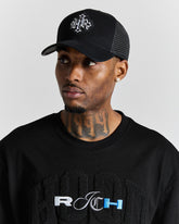 Man wearing a black cap and black shirt with visible branding on a gray background