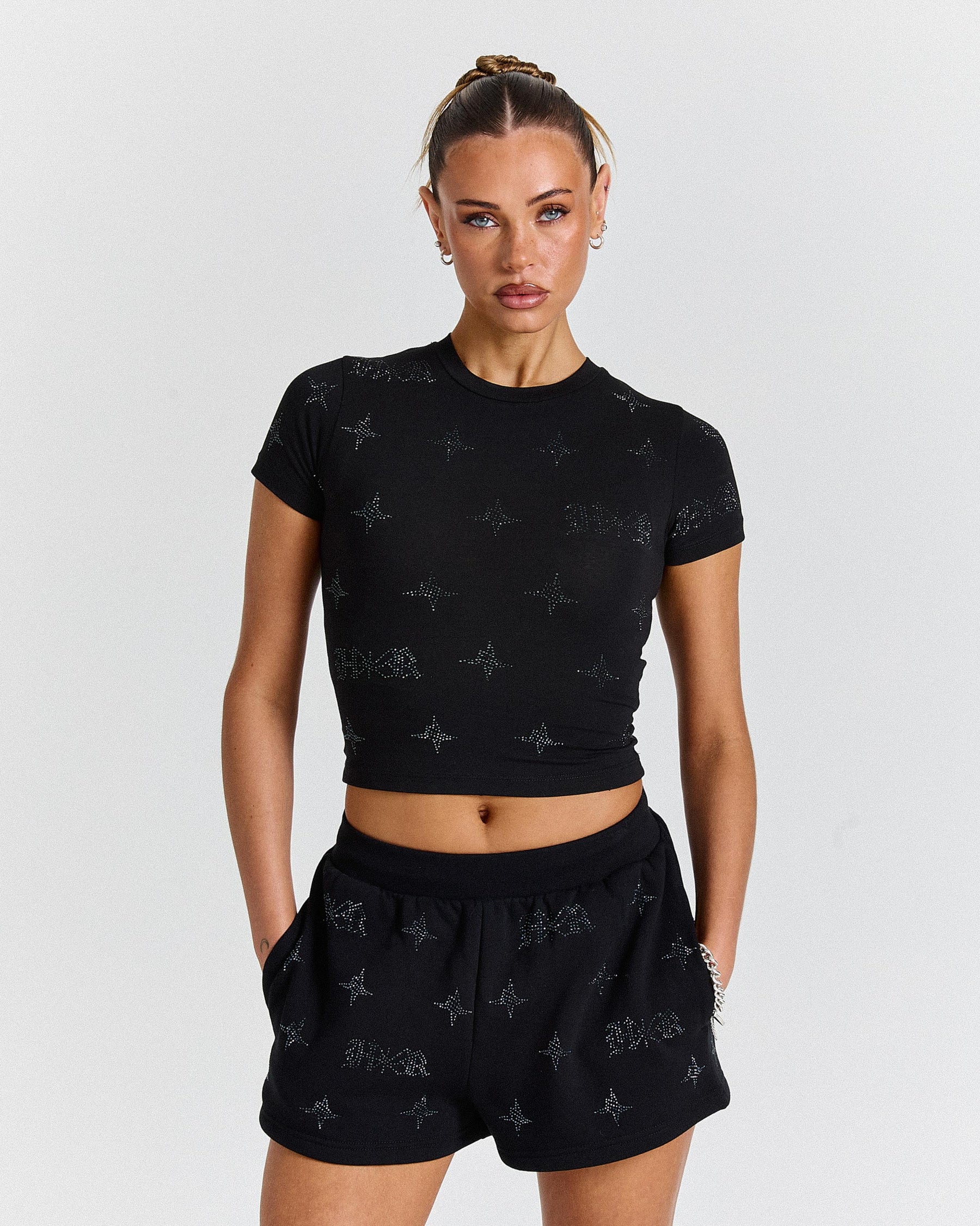 Woman wearing a black crop top and shorts with star pattern on a white background