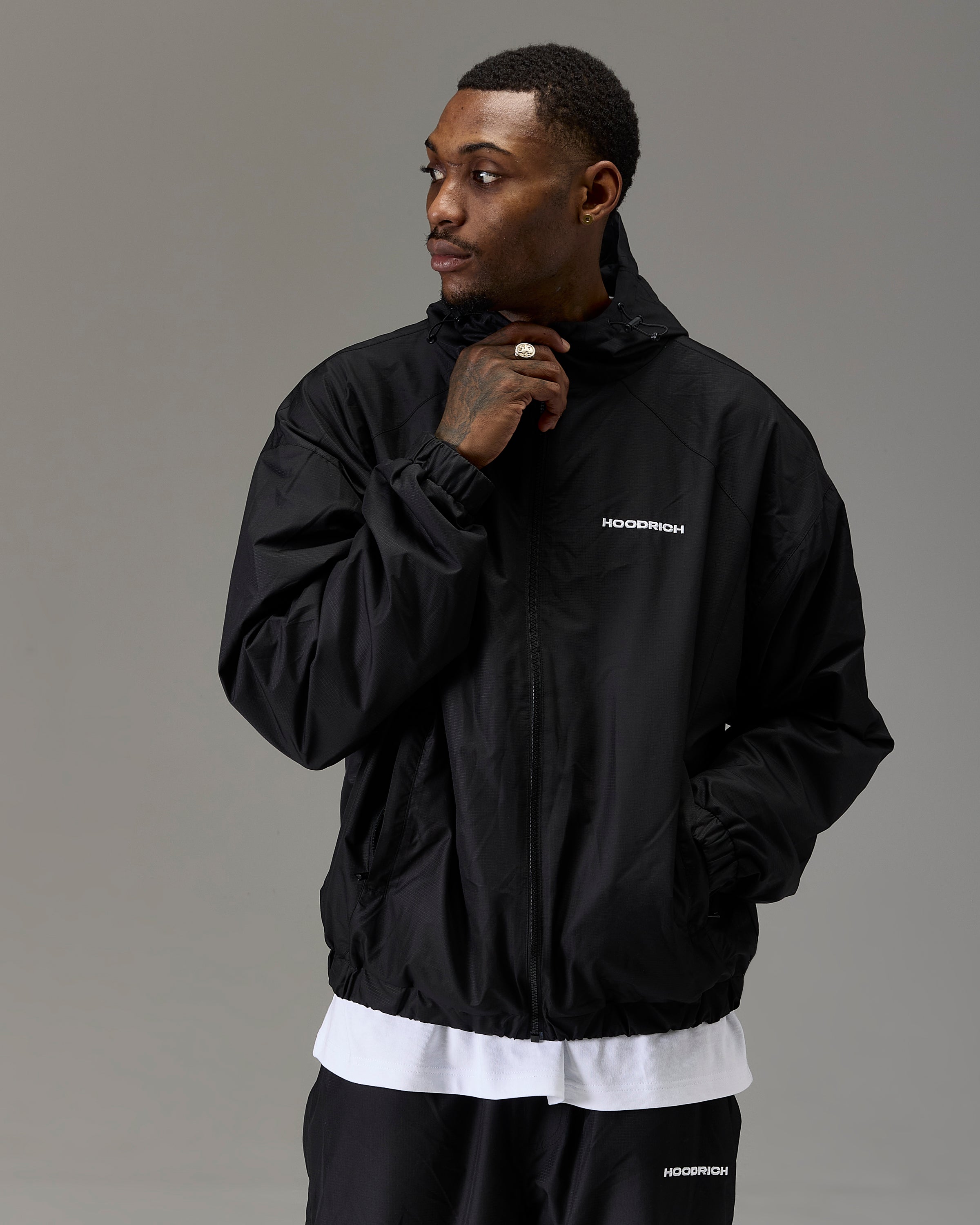 Displays a model wearing the Black 'Hoodrich' branded Men's The Winner's Circle Ripstop Woven Full Tracksuit