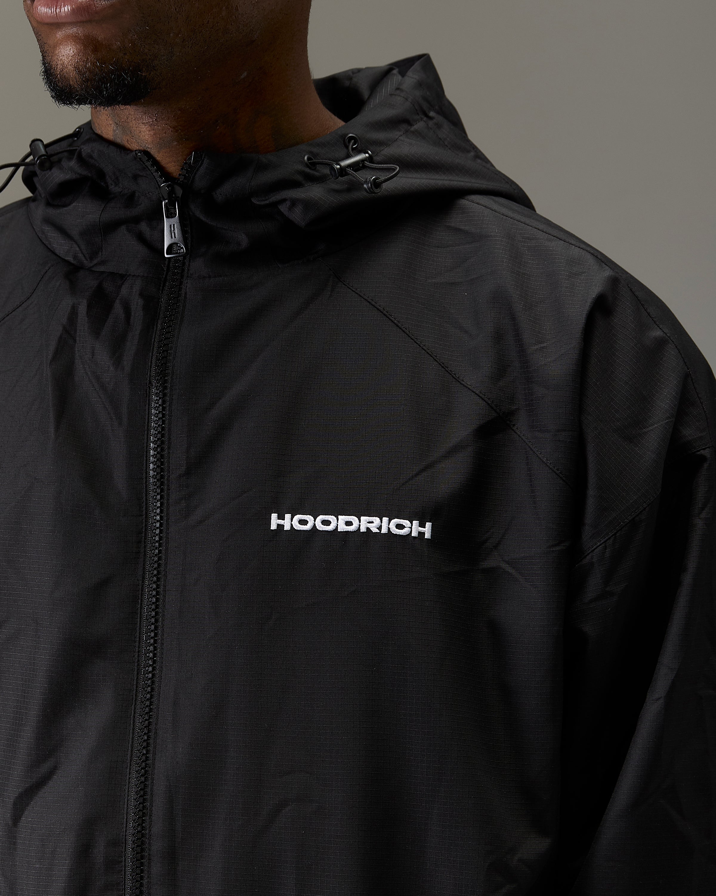 Displays a model wearing the Black 'Hoodrich' branded Men's The Winner's Circle Ripstop Woven Full Tracksuit