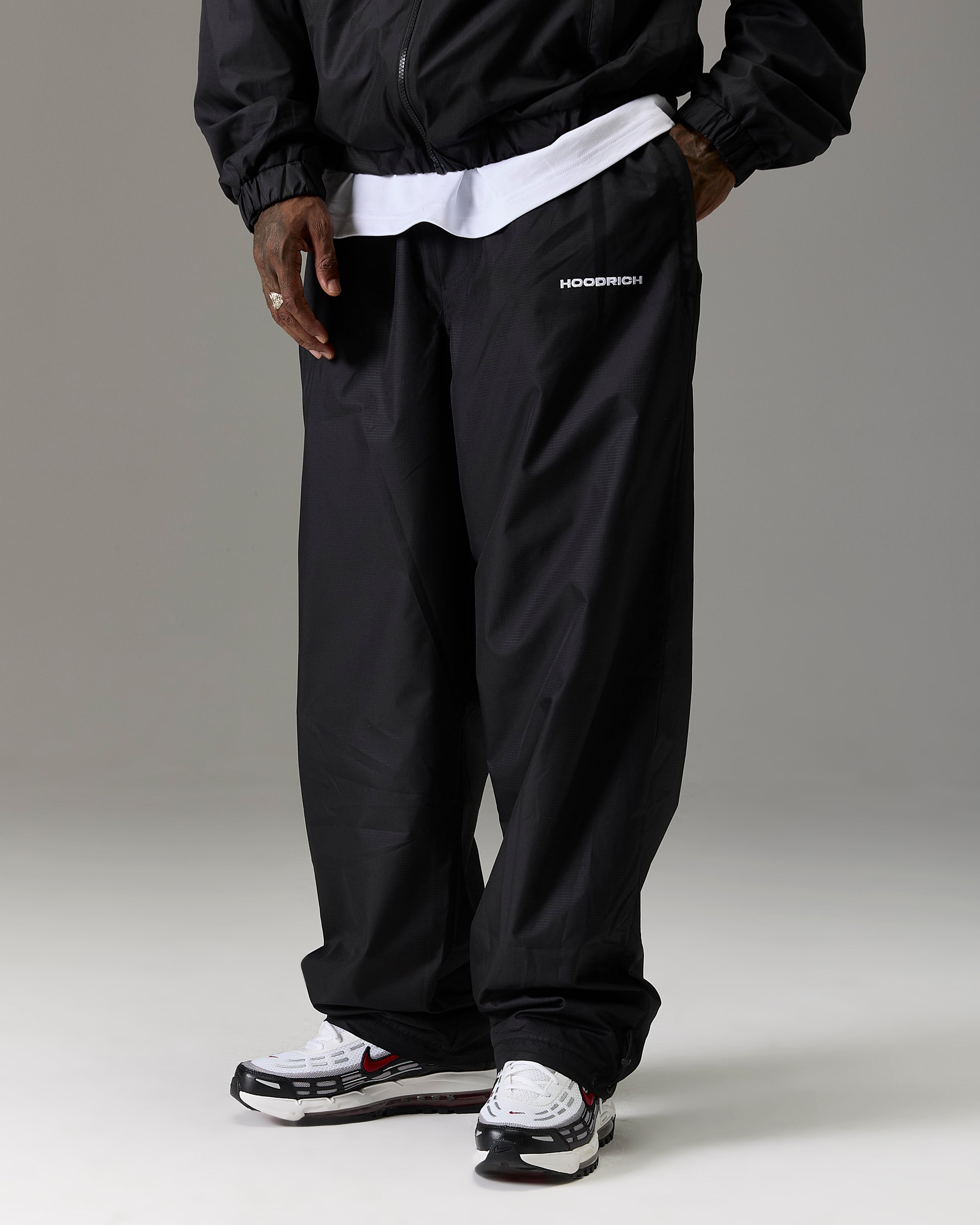 Displays a model wearing the Black 'Hoodrich' branded Men's The Winner's Circle Ripstop Woven Full Tracksuit