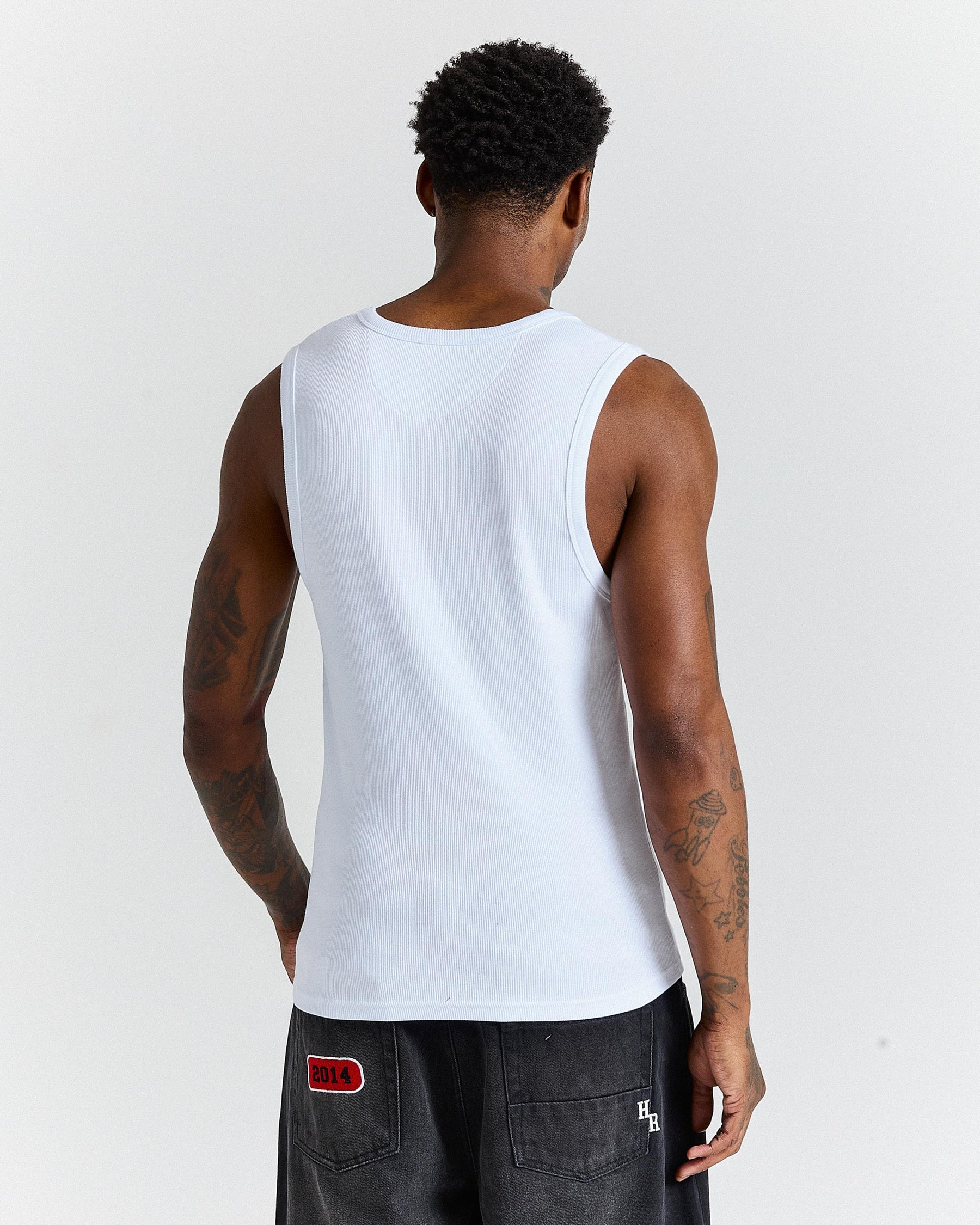 Person wearing a white tank top against a plain background