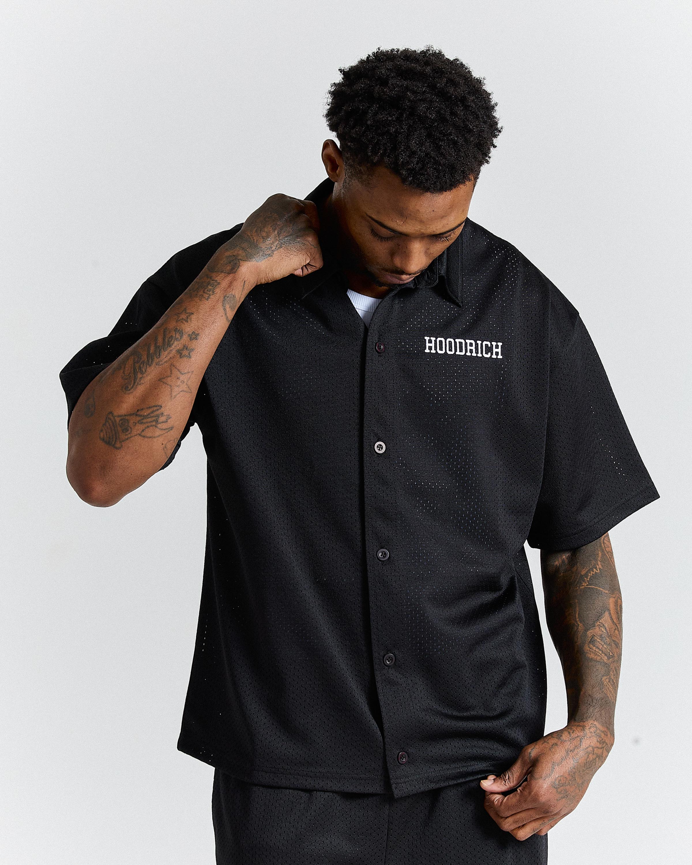 Man wearing a black 'Hoodrich' shirt on a white background