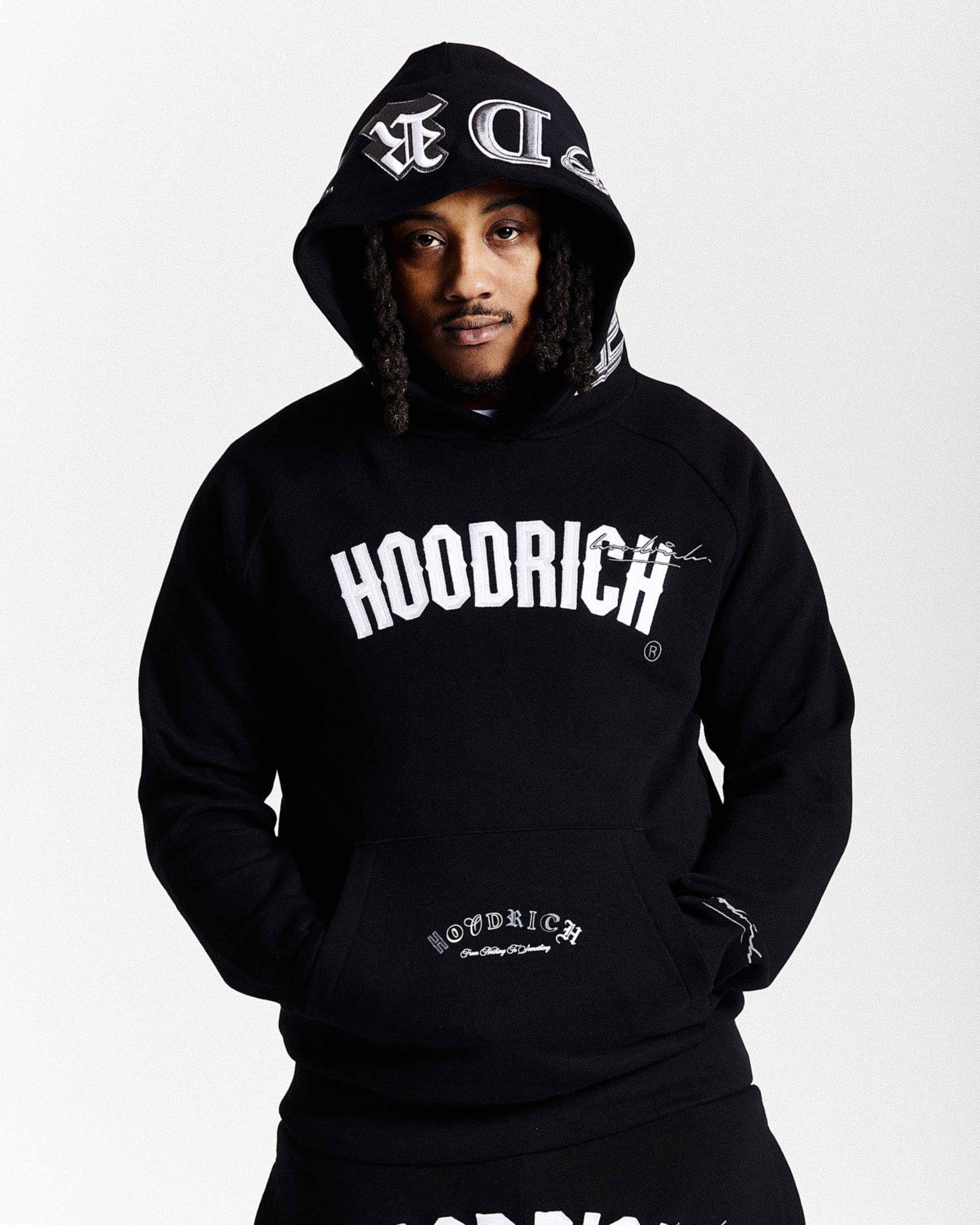 Person wearing a black 'Hoodrich' hoodie with branding on a white background