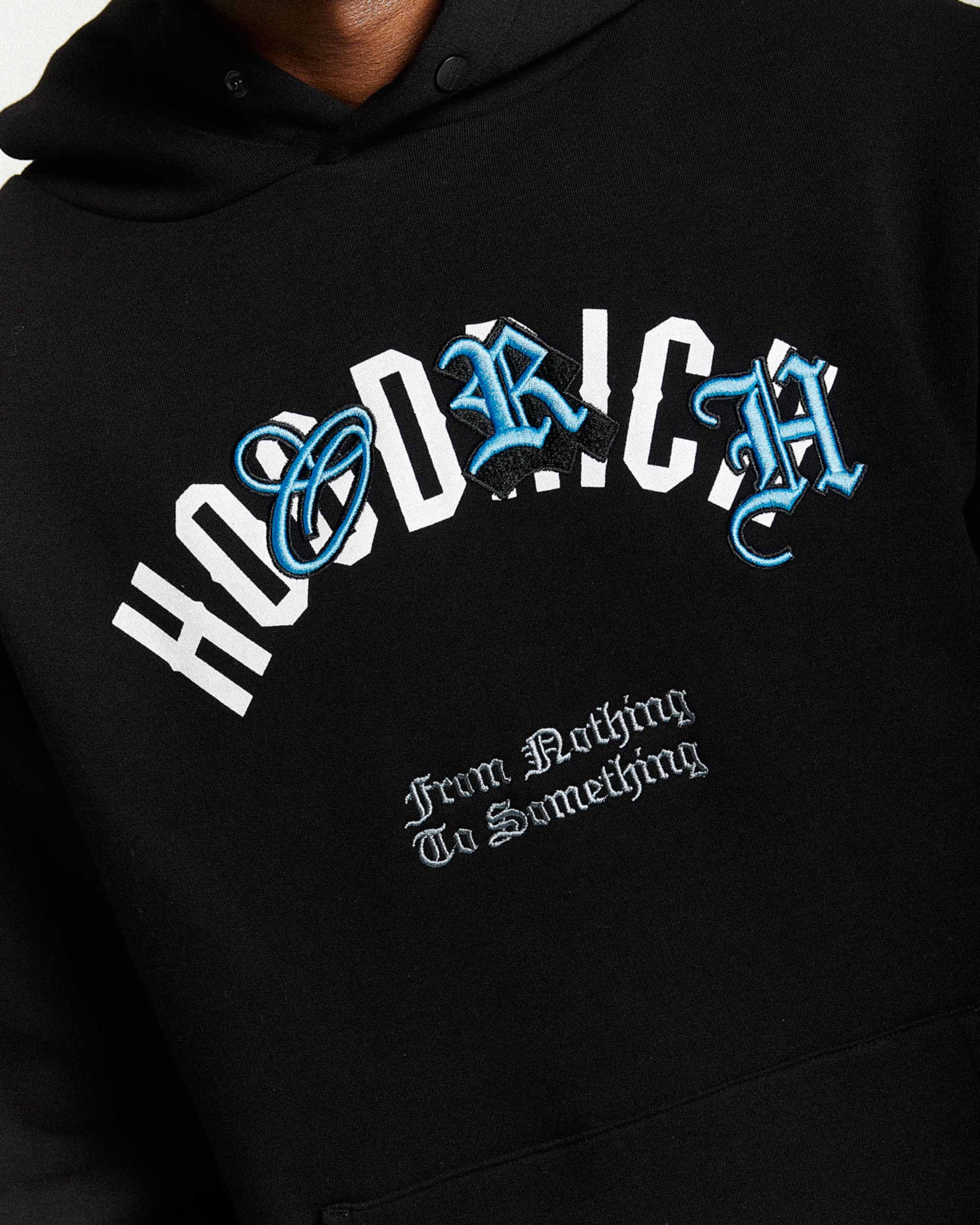 Displays a model wearing the Black 'Hoodrich' branded men's Shadow Full Tracksuit
