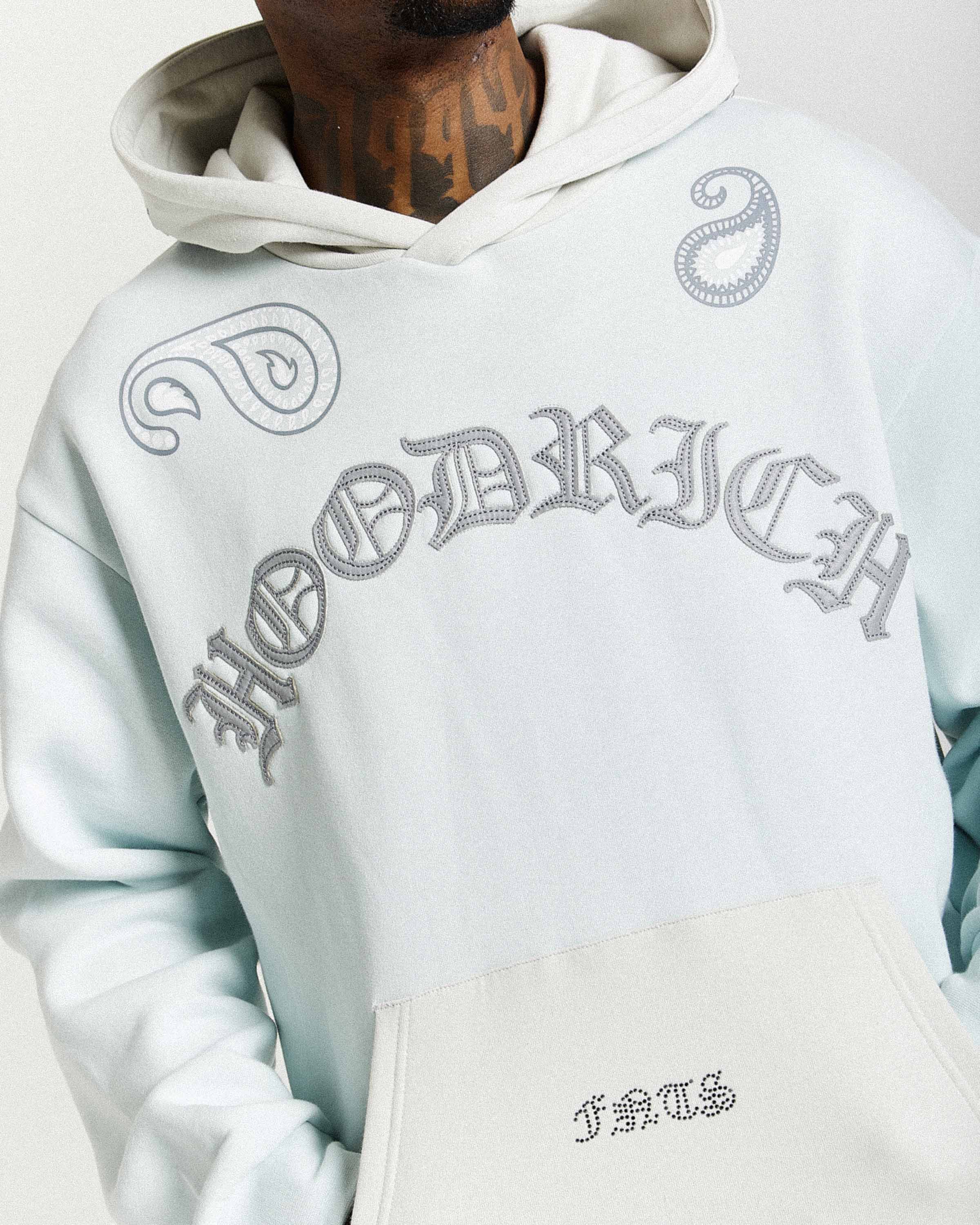 Light blue hoodie with embroidered text on a plain background