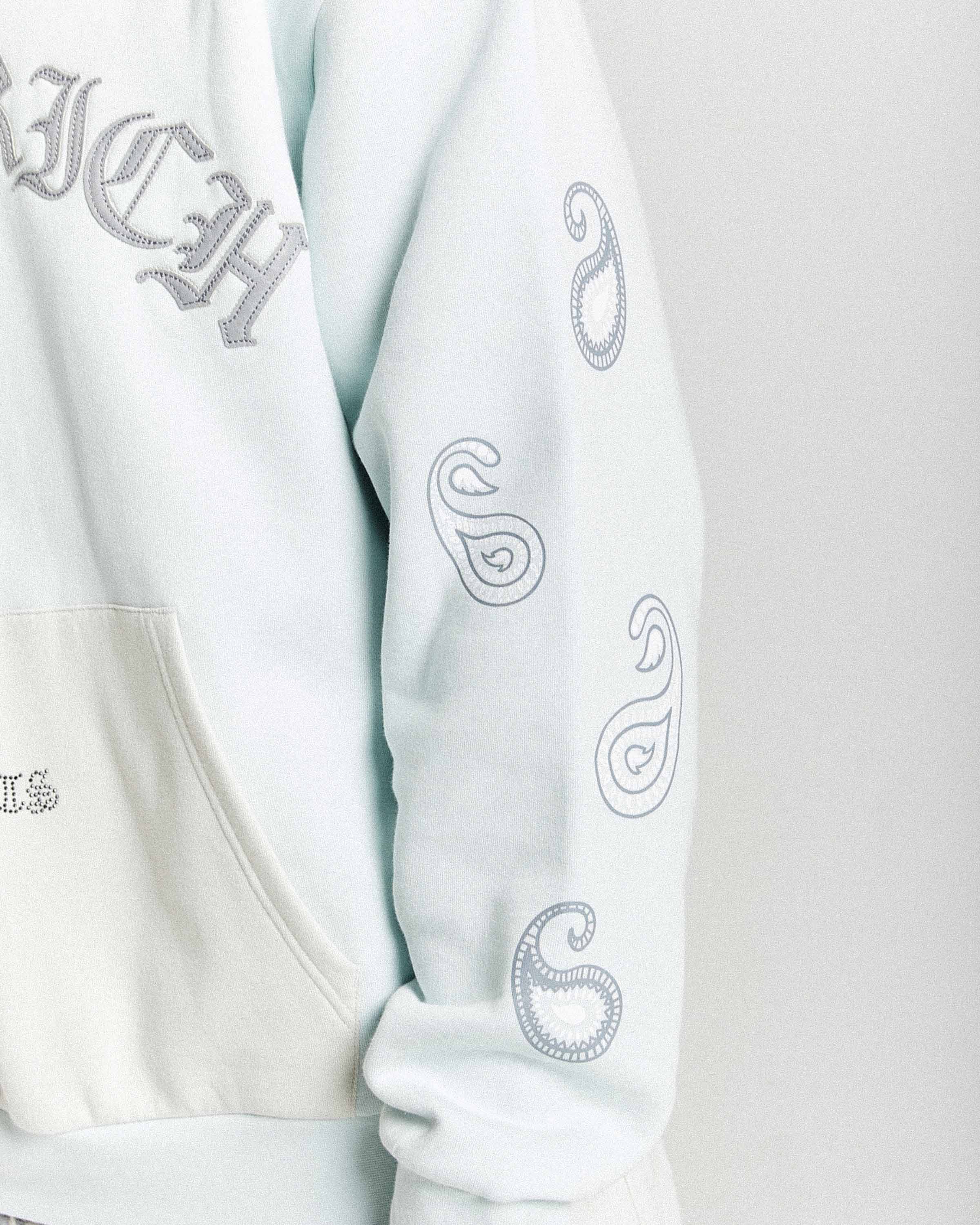 Light blue sweatshirt with embroidered designs on a white background