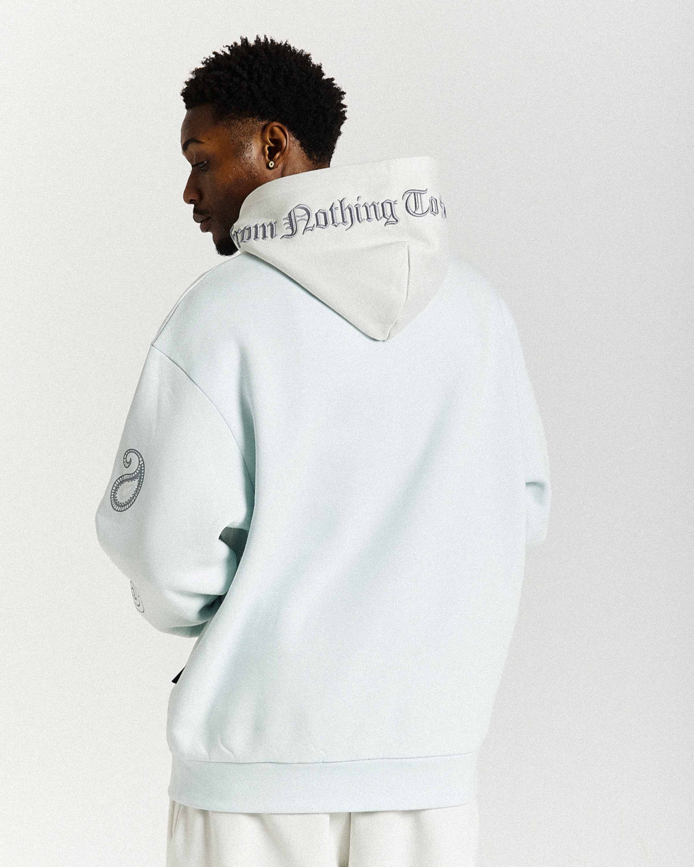 Person wearing a light gray hoodie with text on the back against a white background