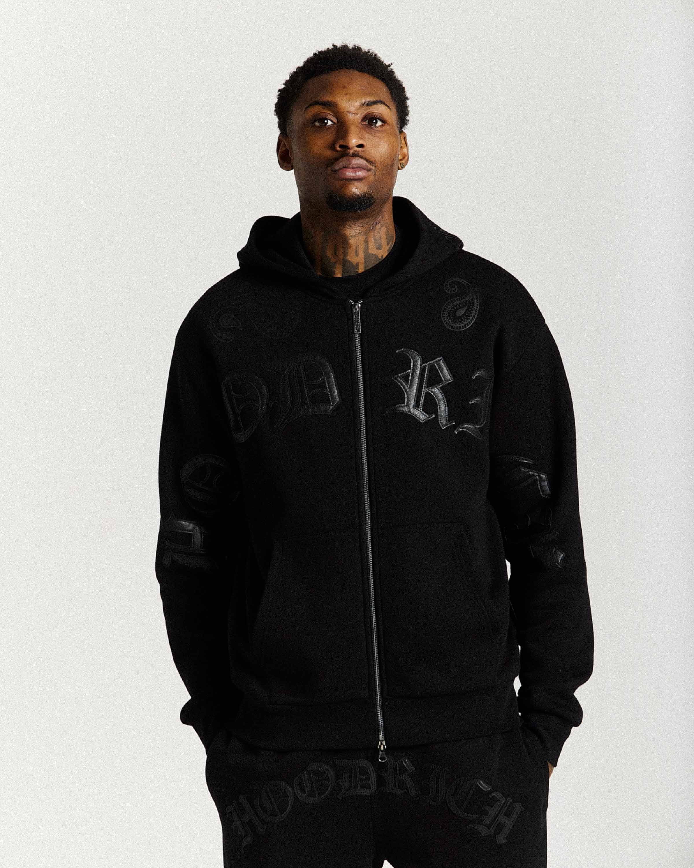 Person wearing a black hoodie with branding on a white background