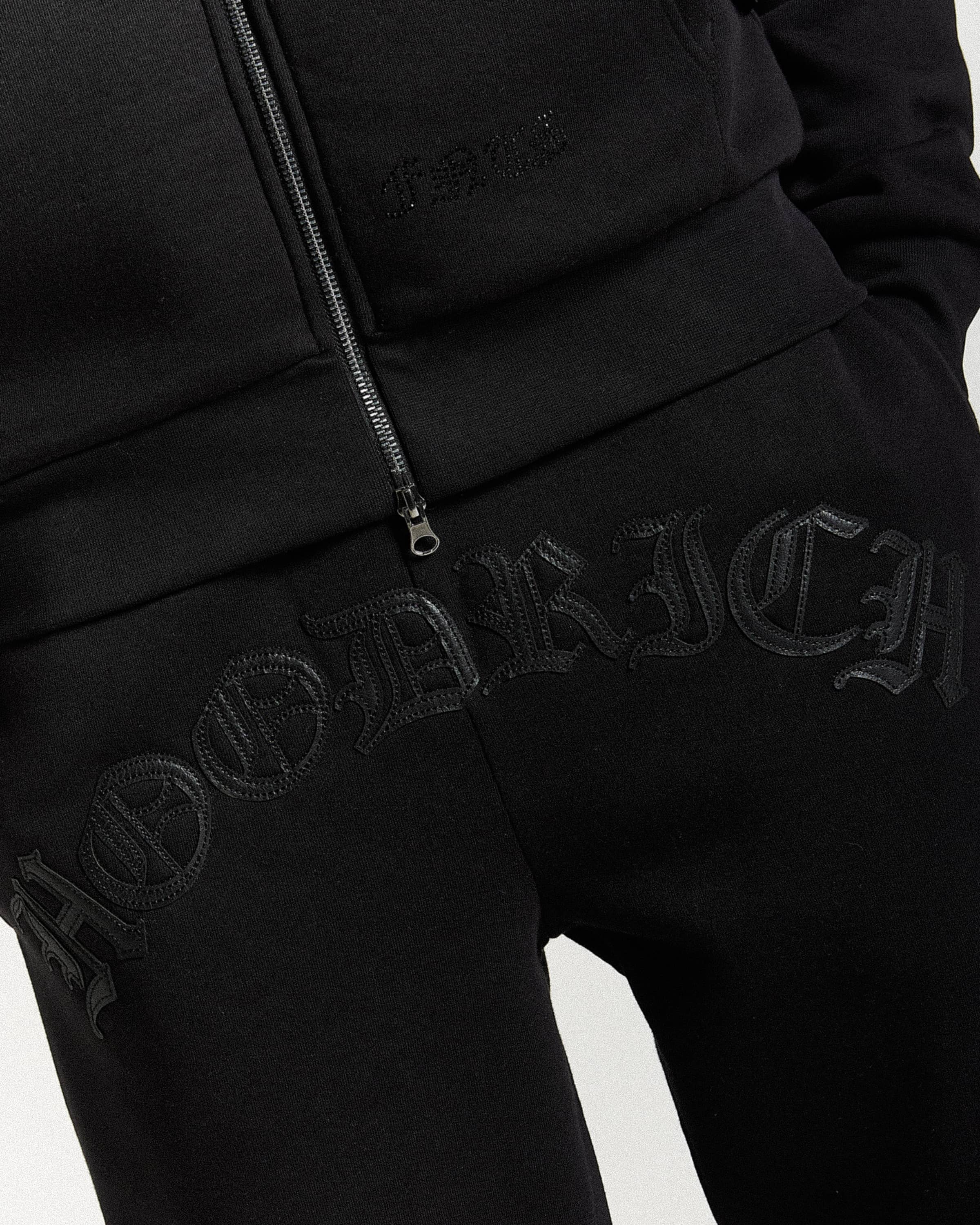 Displays a model wearing the Black 'Hoodrich' branded men's Inkline Full Tracksuit