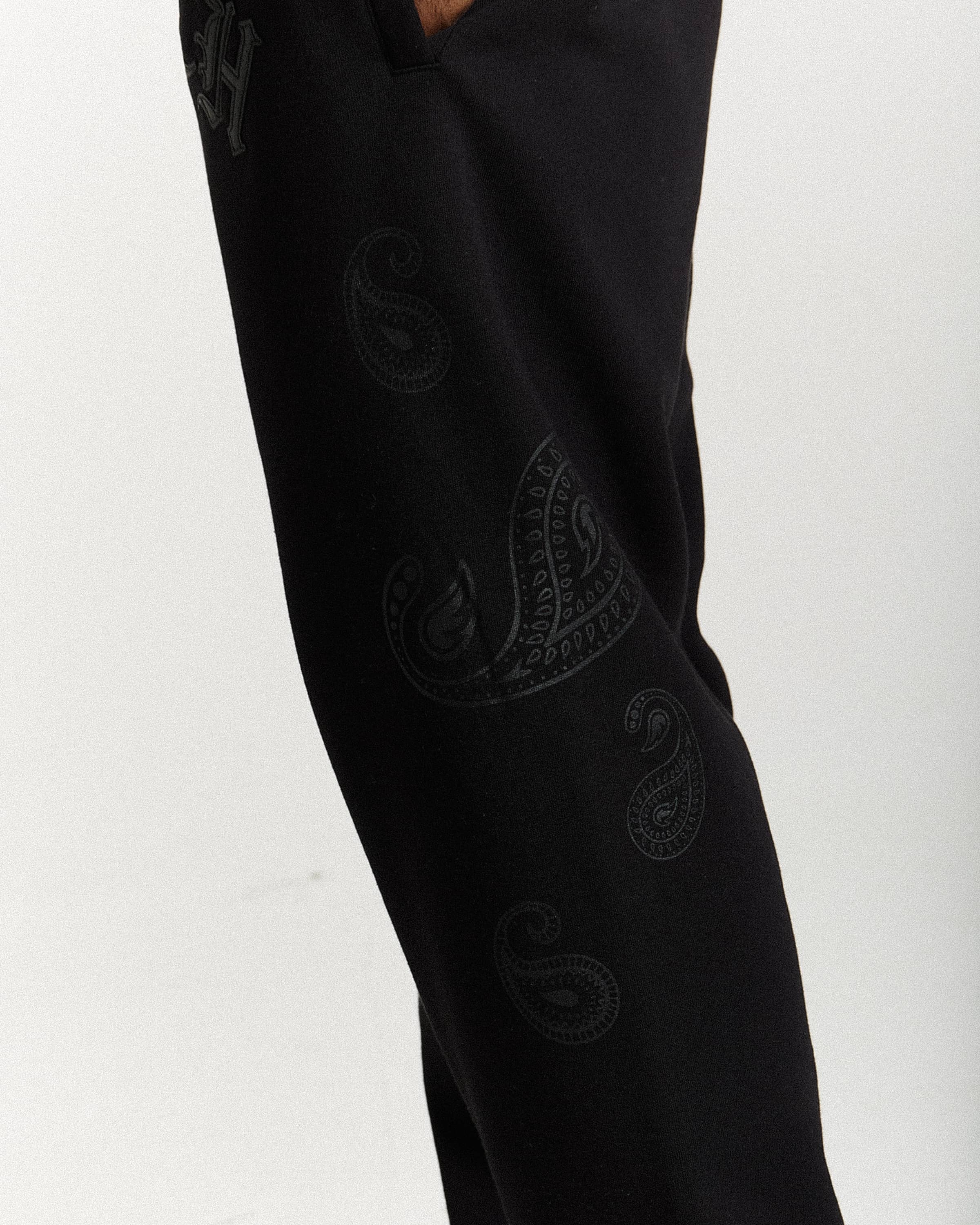 Black pants with embroidered patterns on a white background