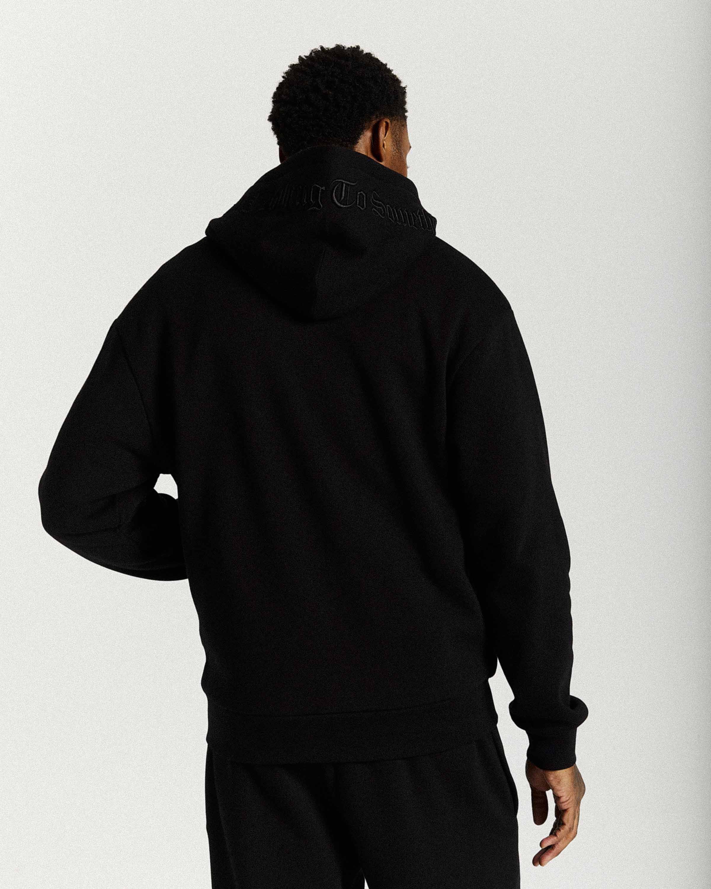 Displays a model wearing the Black 'Hoodrich' branded men's Inkline Full Tracksuit